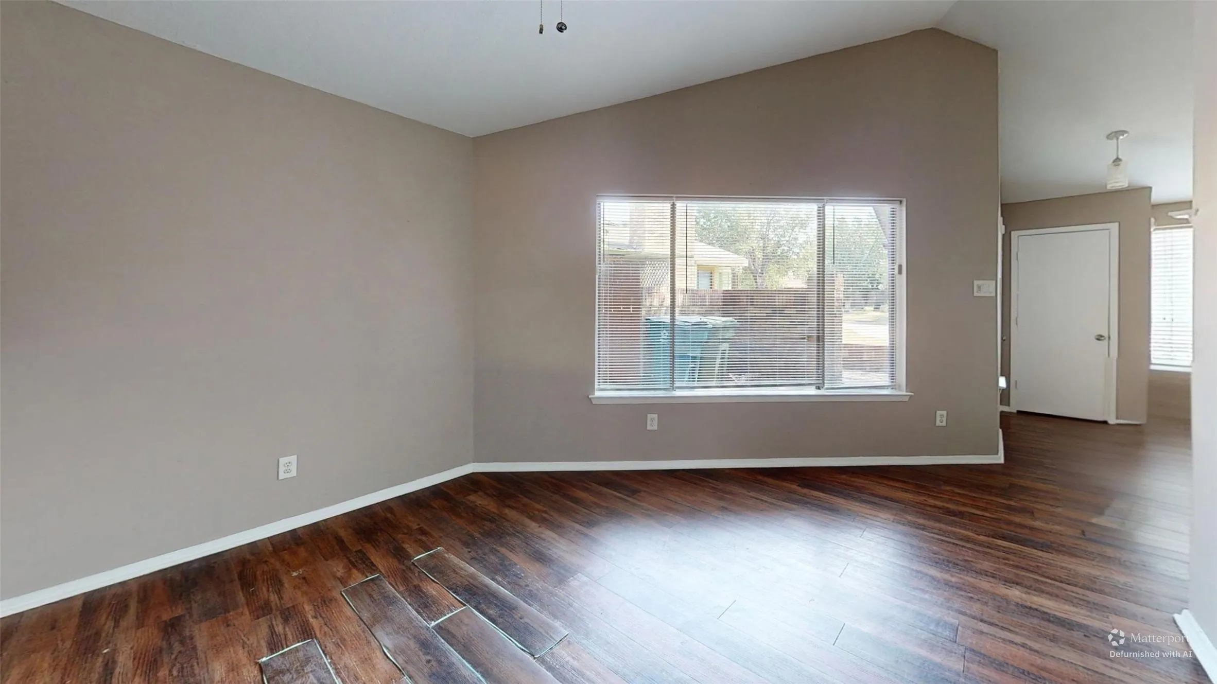 Vaulted ceiling, wood-finish flooring, large window, neutral wall paint, and white trim