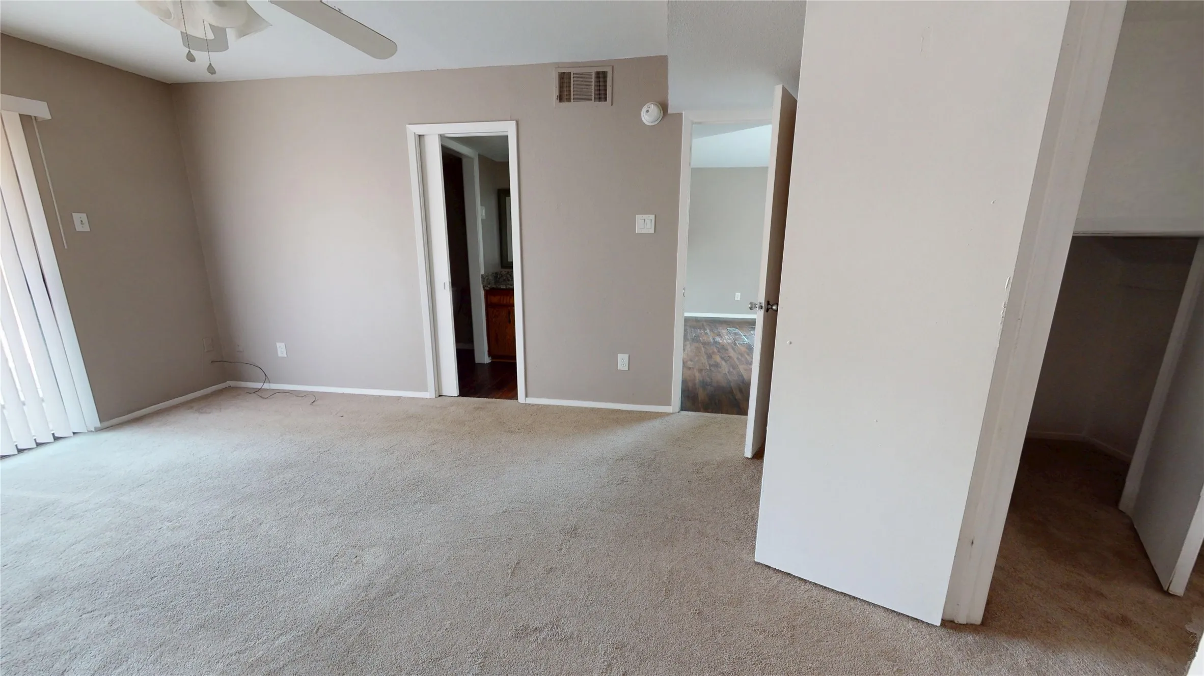 Carpeted room with neutral wall paint and a ceiling fan