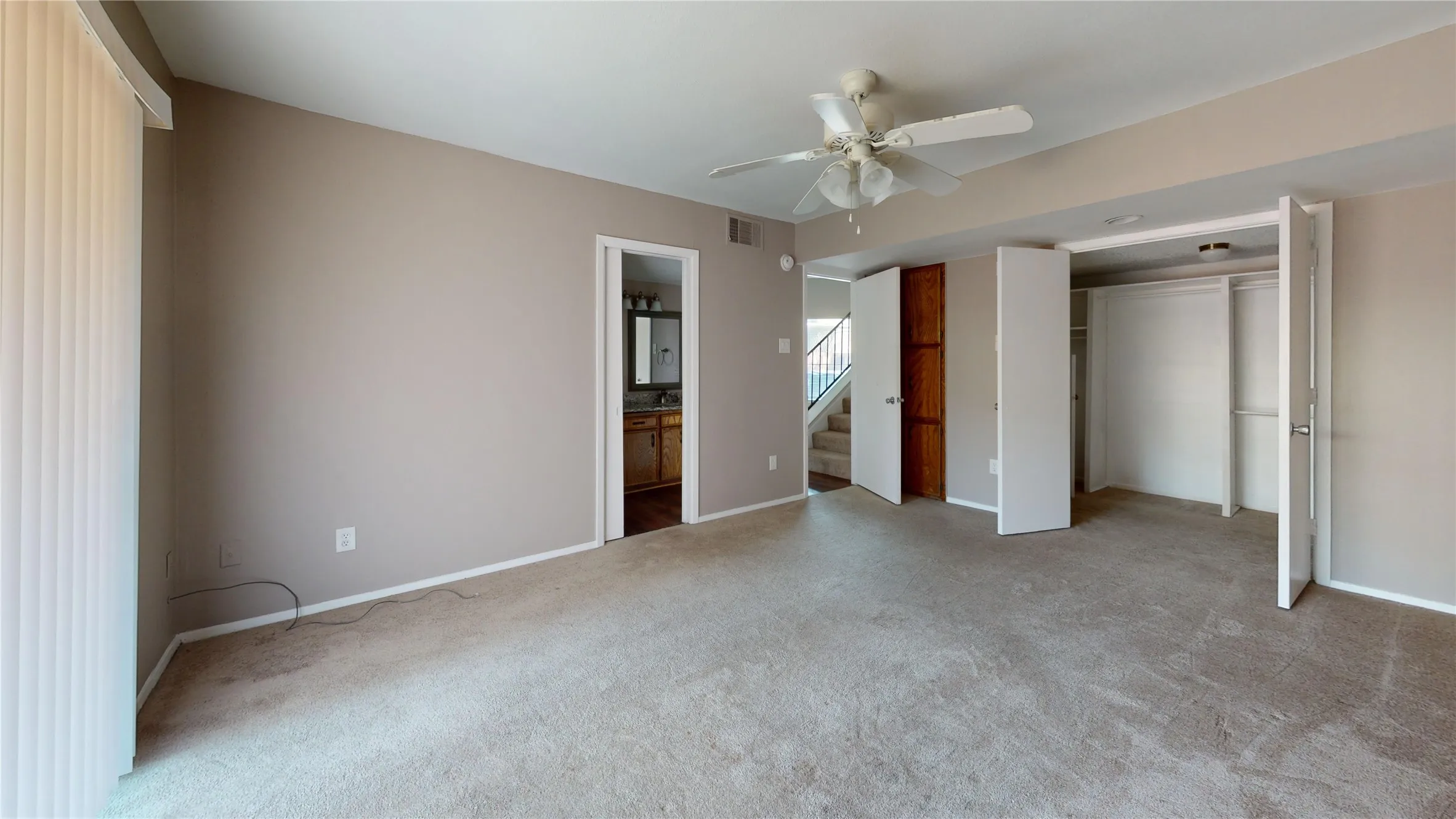 Carpeted flooring, ceiling fan, bi-fold closet doors, vertical blinds, and a built-in storage cabinet