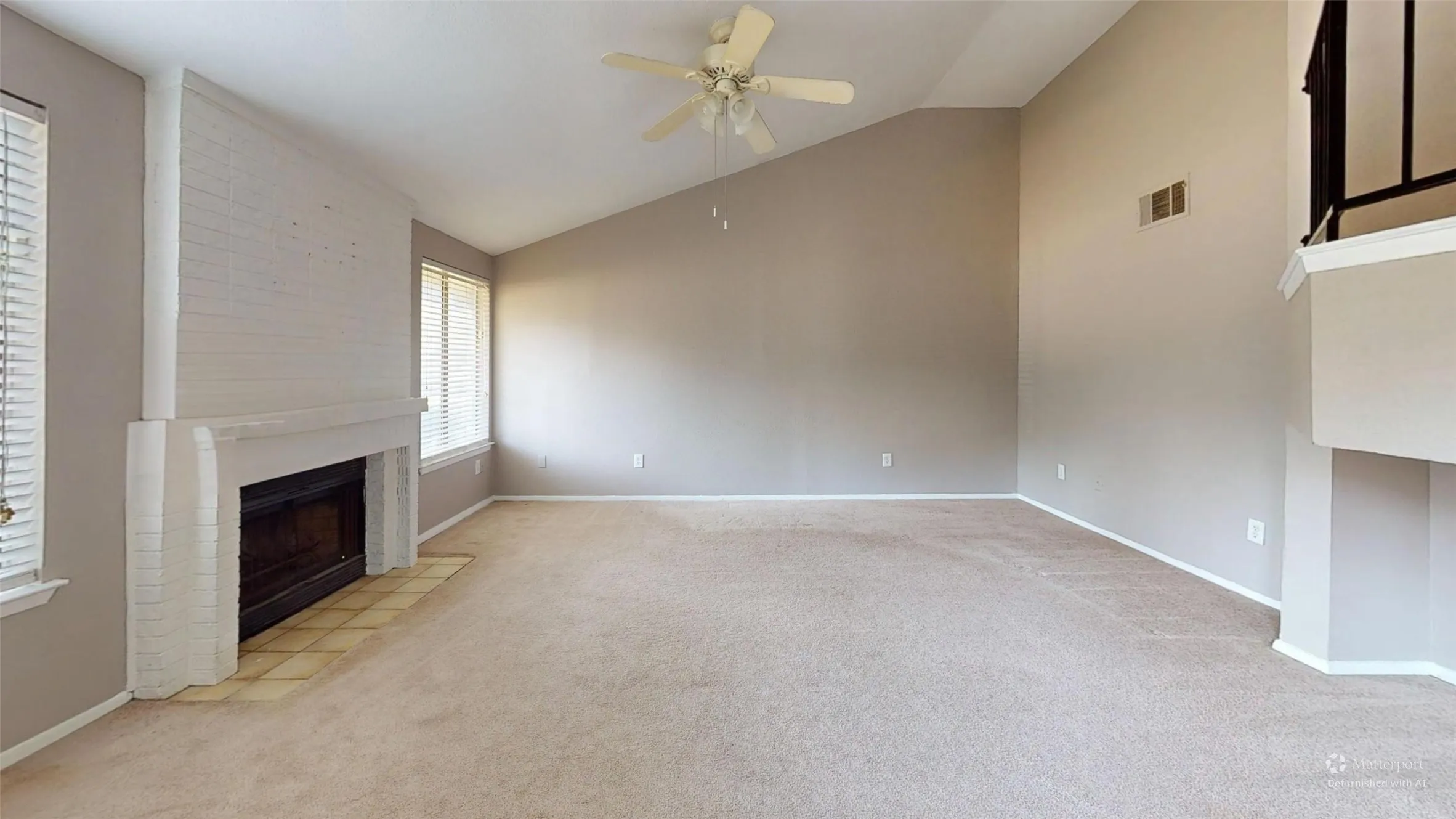 Vaulted ceilings, a ceiling fan, a fireplace with a brick surround, and multiple windows