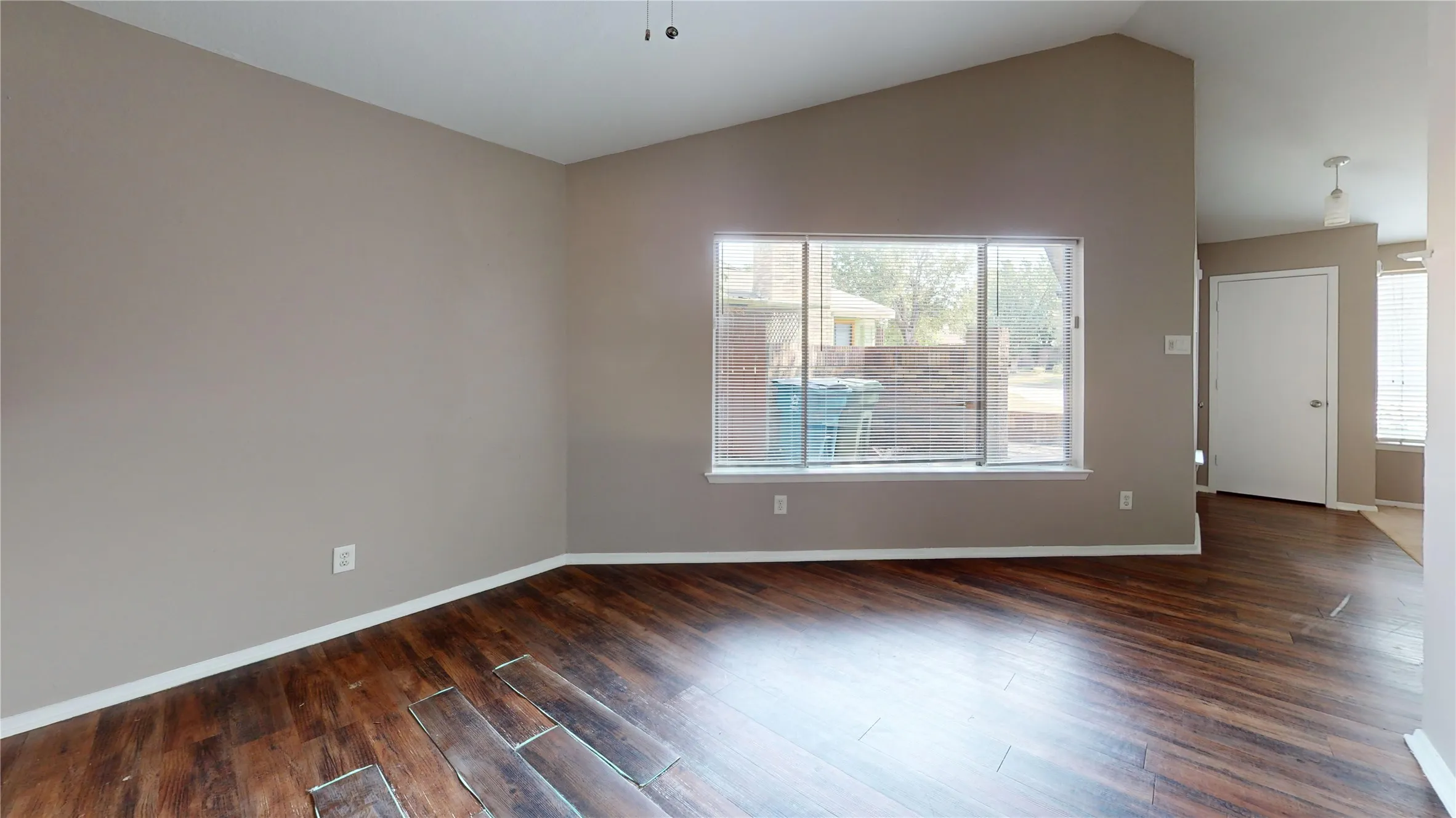 Vaulted ceiling with a ceiling fan, wood-finish flooring, and a large window