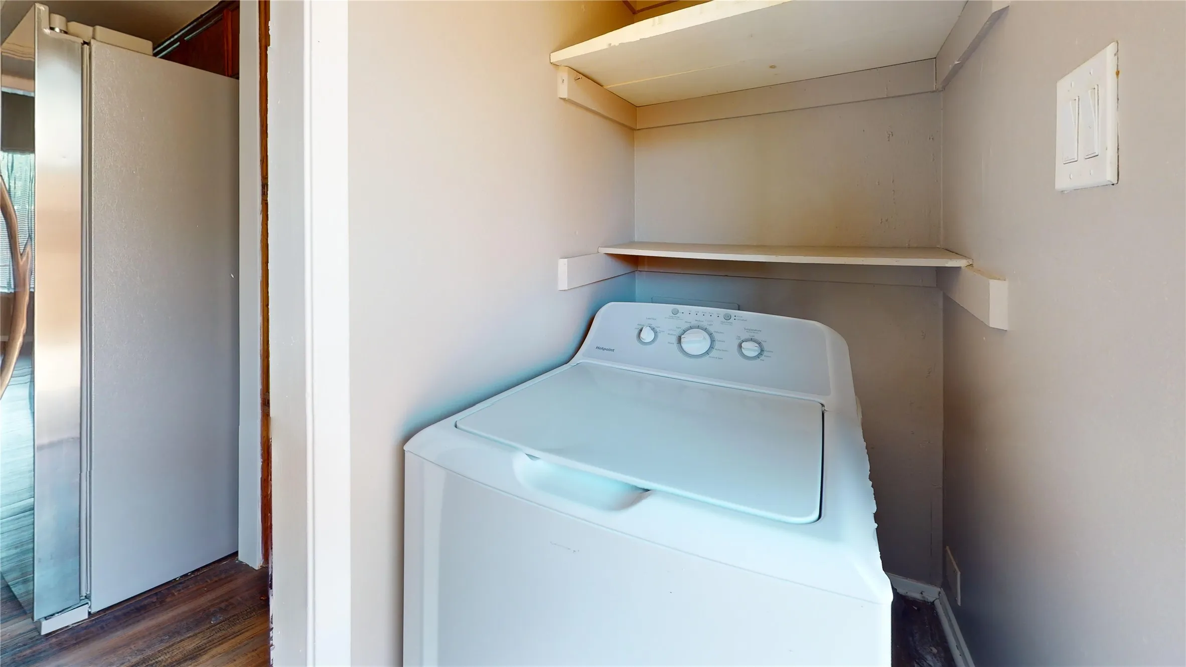 Dedicated laundry area with built-in shelving and wood-finish flooring