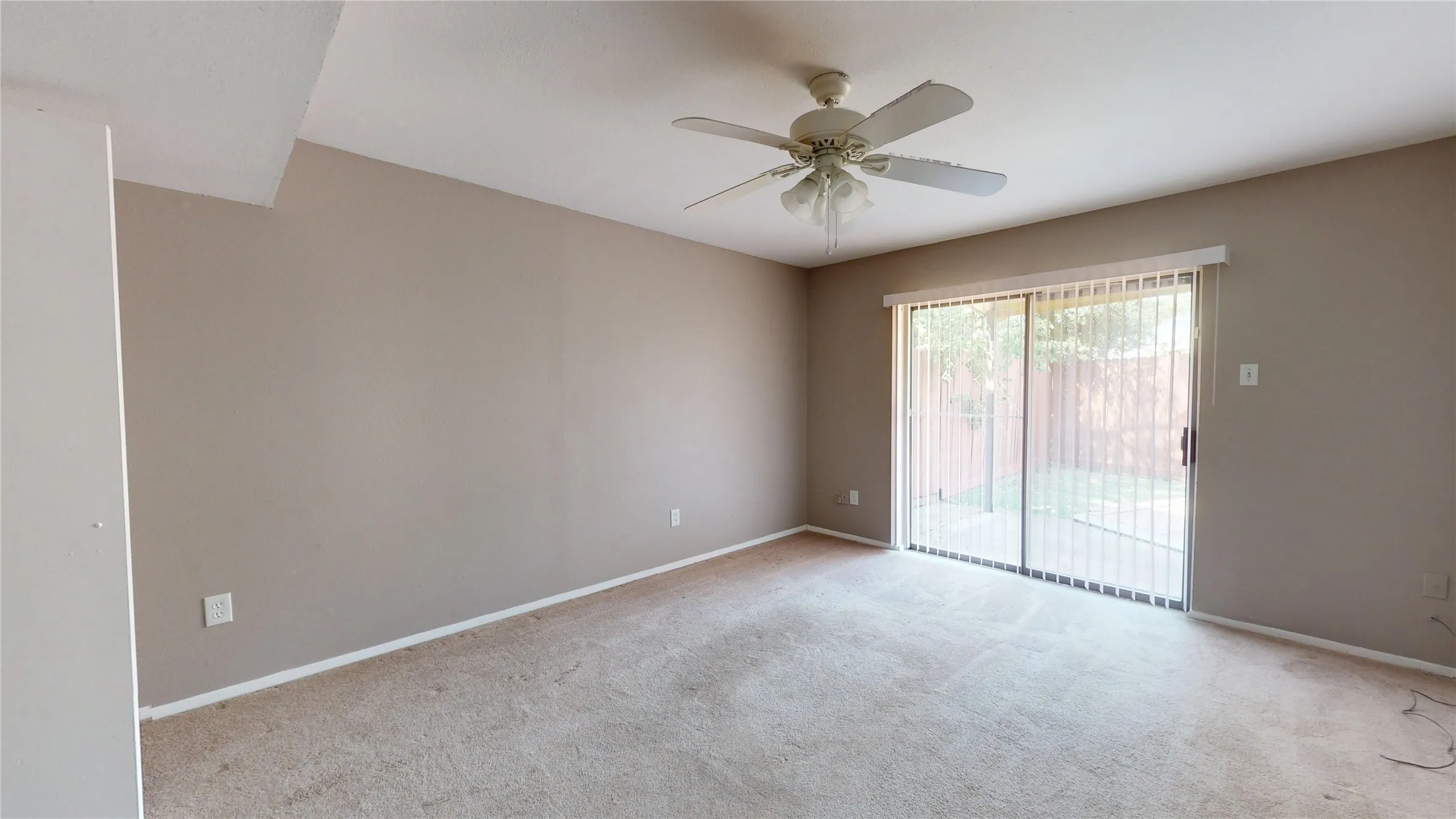 Carpeted flooring, ceiling fan with integrated lighting, neutral wall tones, and glass sliding door access to an exterior patio