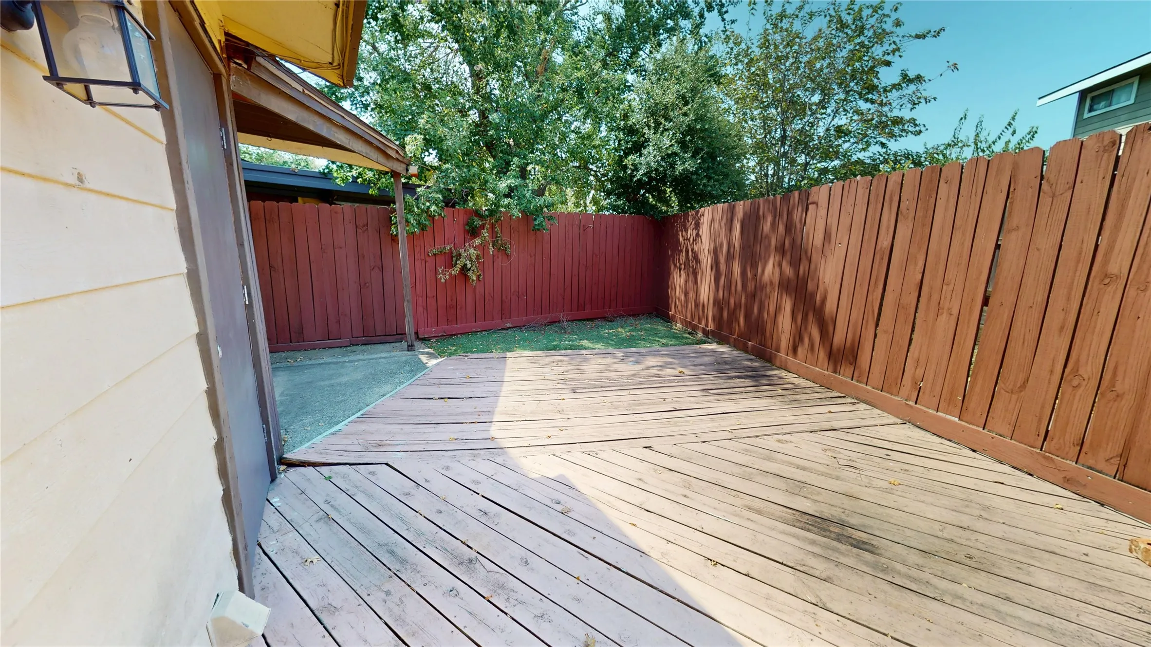 Outdoor space featuring a wood deck, concrete patio, and a painted wood privacy fence