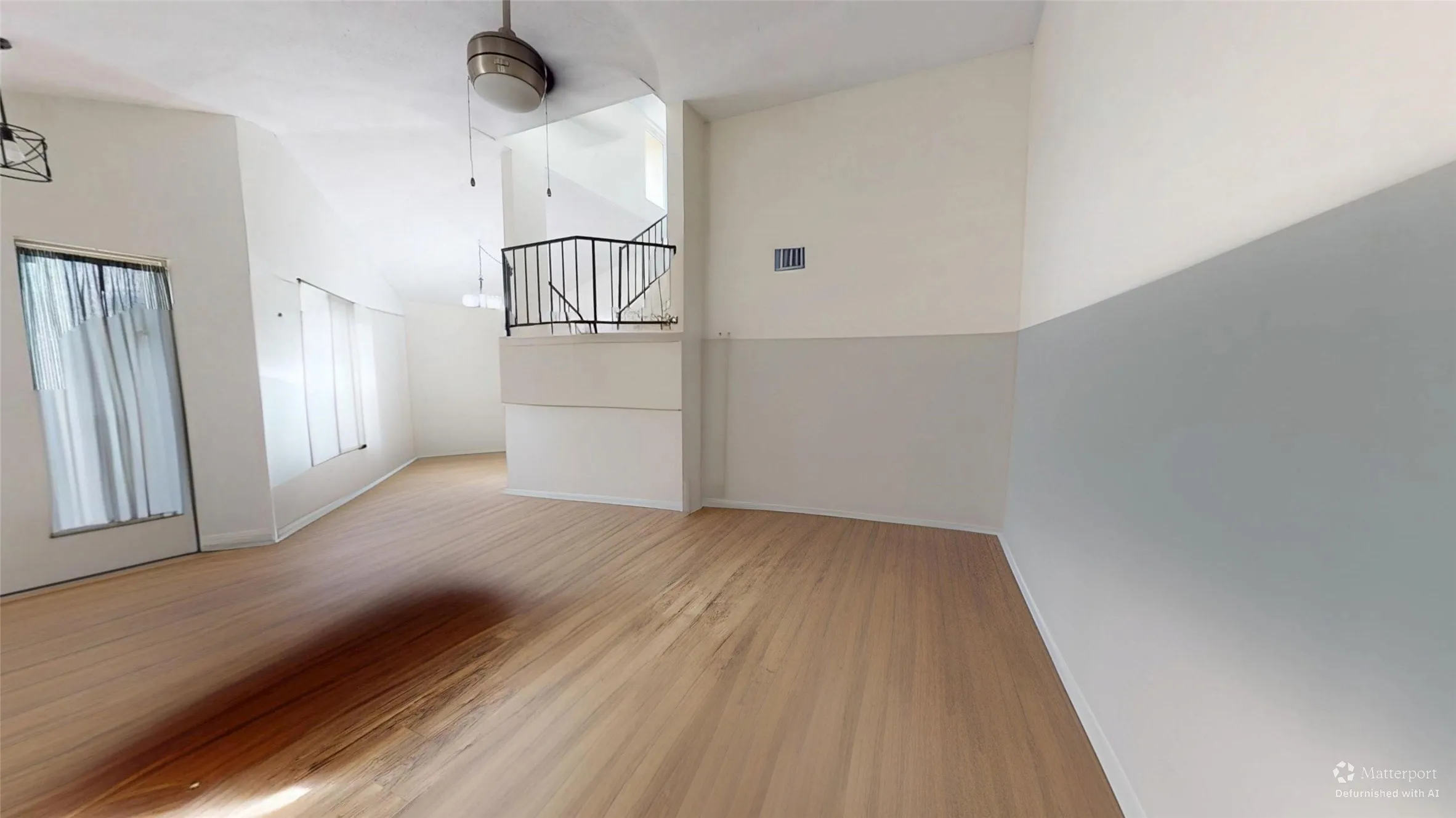 Vaulted ceiling, wood-finish flooring, half-wall, interior balcony with metal railing, and ceiling fan