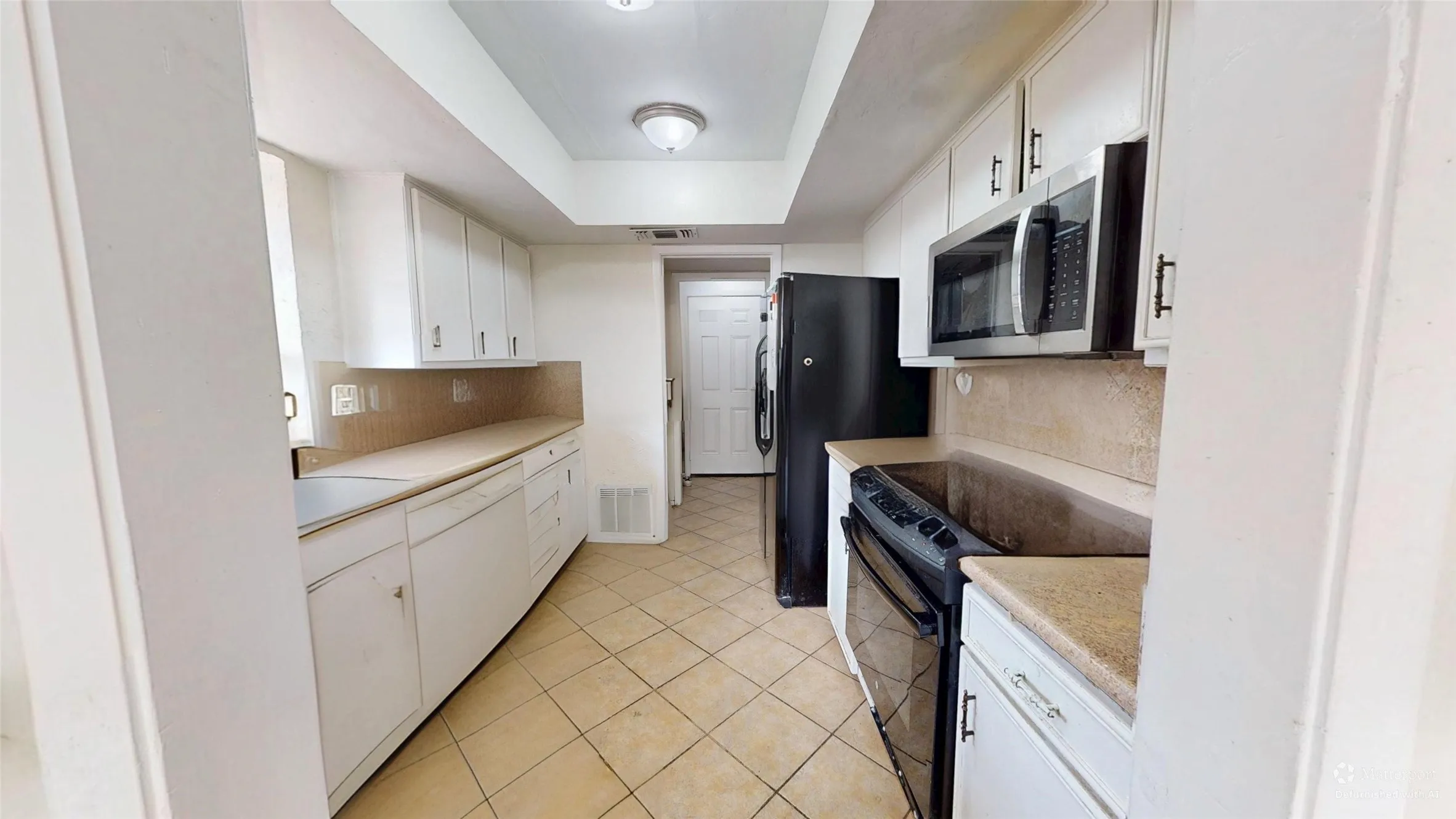 Kitchen featuring white cabinetry, tile flooring, light countertops, and stainless steel microwave
