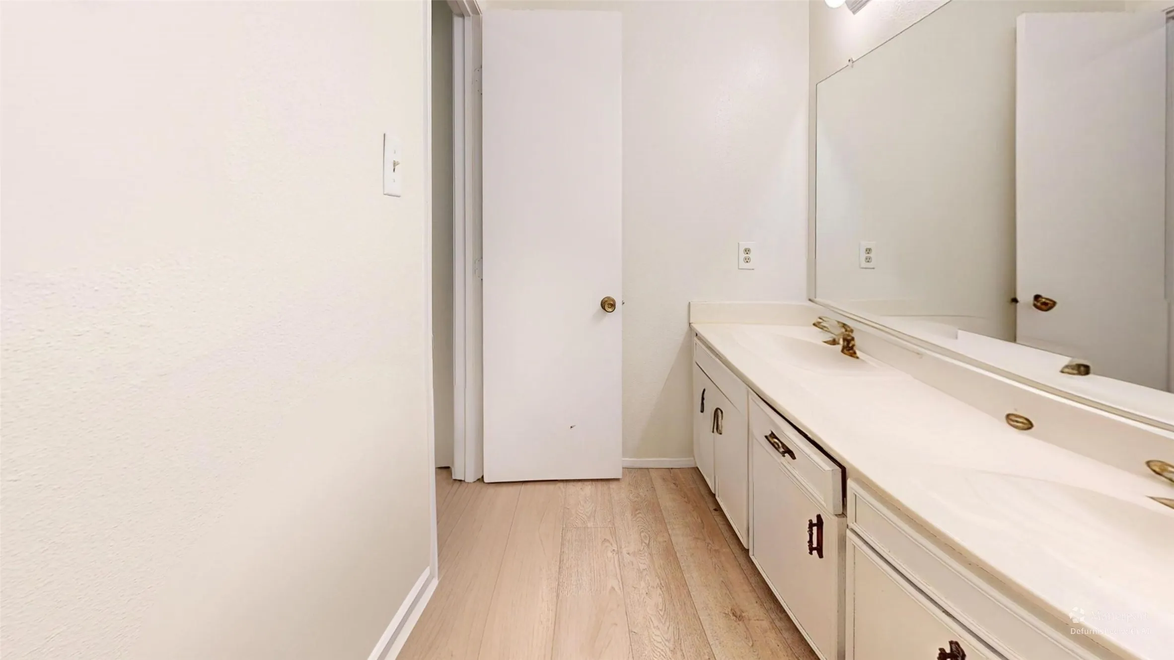 Dual vanity with integrated sinks, expansive mirror, wall-mounted light fixture, and wood-finish flooring