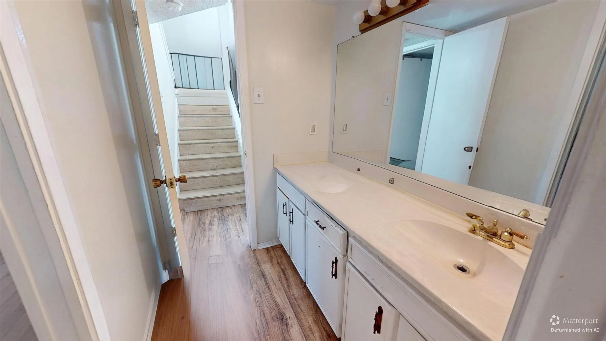 Dual vanity with white countertops, wood-finish flooring, and integrated sinks