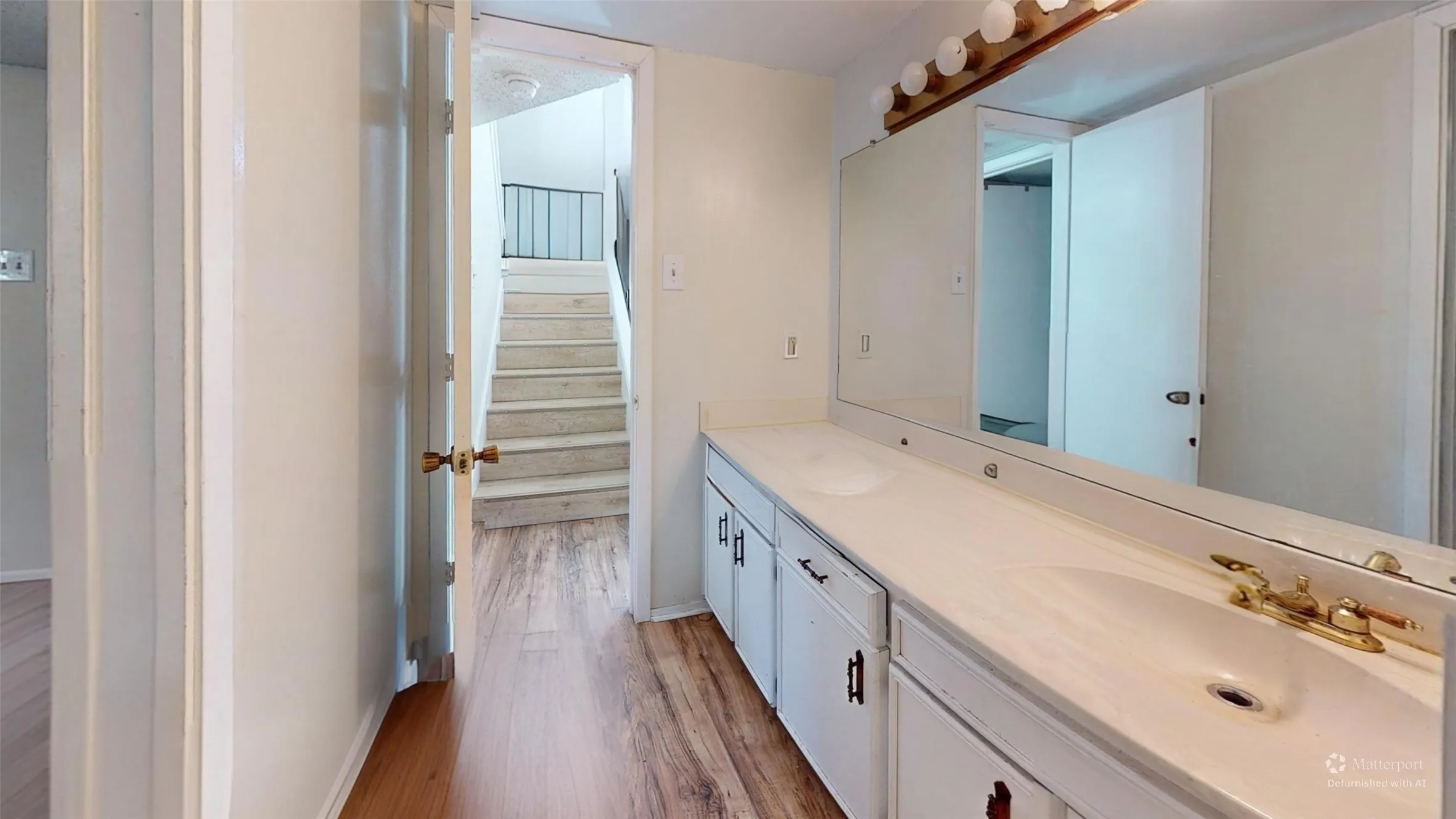 Double vanity with integrated sinks, brass-tone fixtures, and white cabinetry