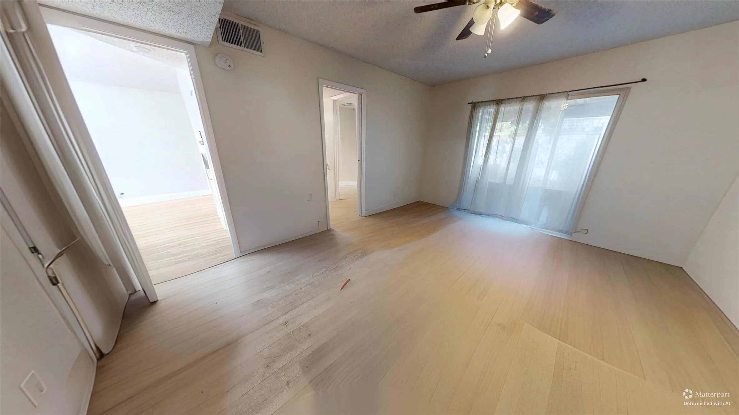 Light wood-finish flooring throughout, ceiling fan with integrated lighting, and multiple doorways