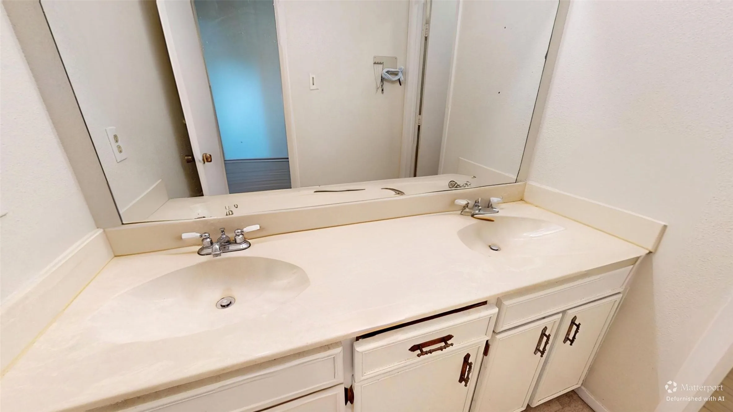 Double vanity with integrated sinks, white cabinetry, and a large wall-mounted mirror