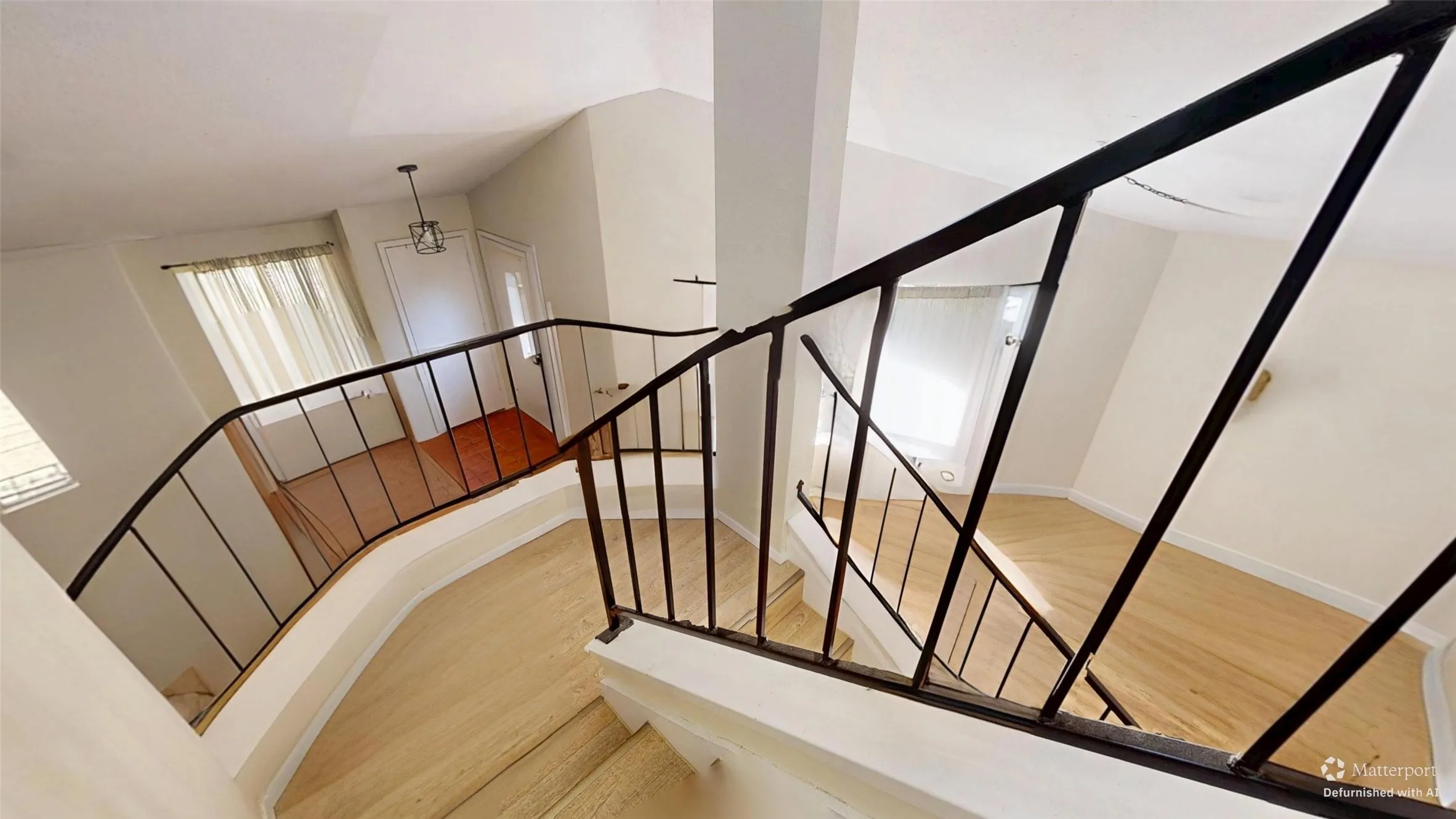 Two-story entryway with light wood-finish flooring, white walls, and a wrought iron staircase