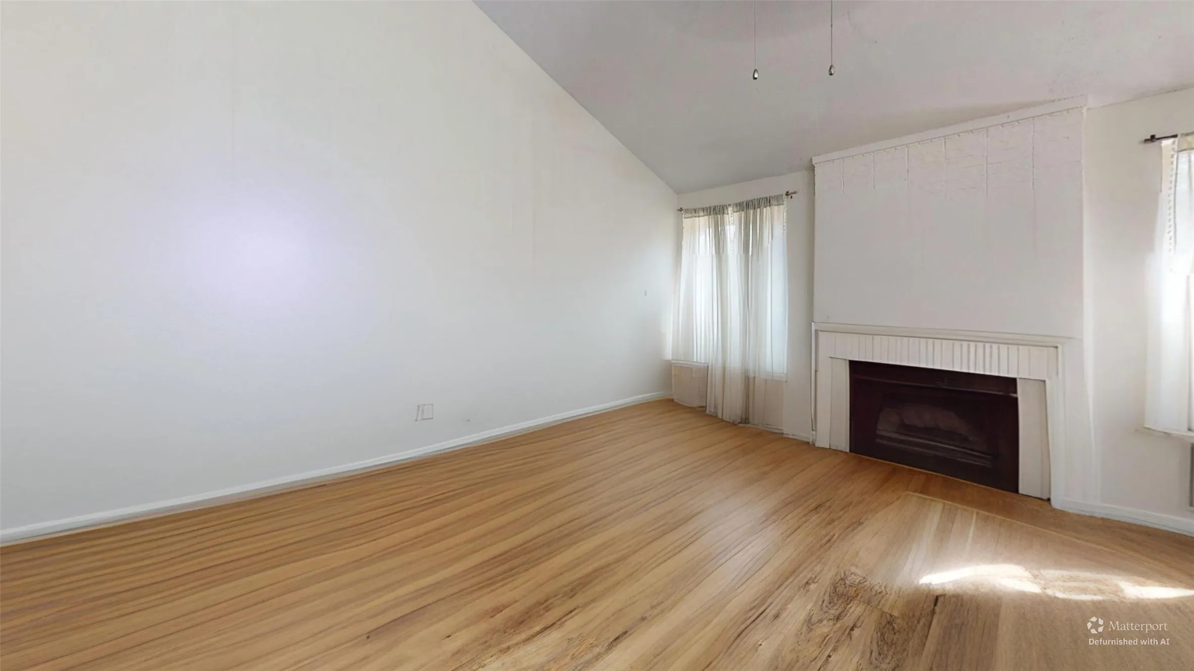 Vaulted ceiling, wood-finish flooring, fireplace with white mantle, and multiple windows