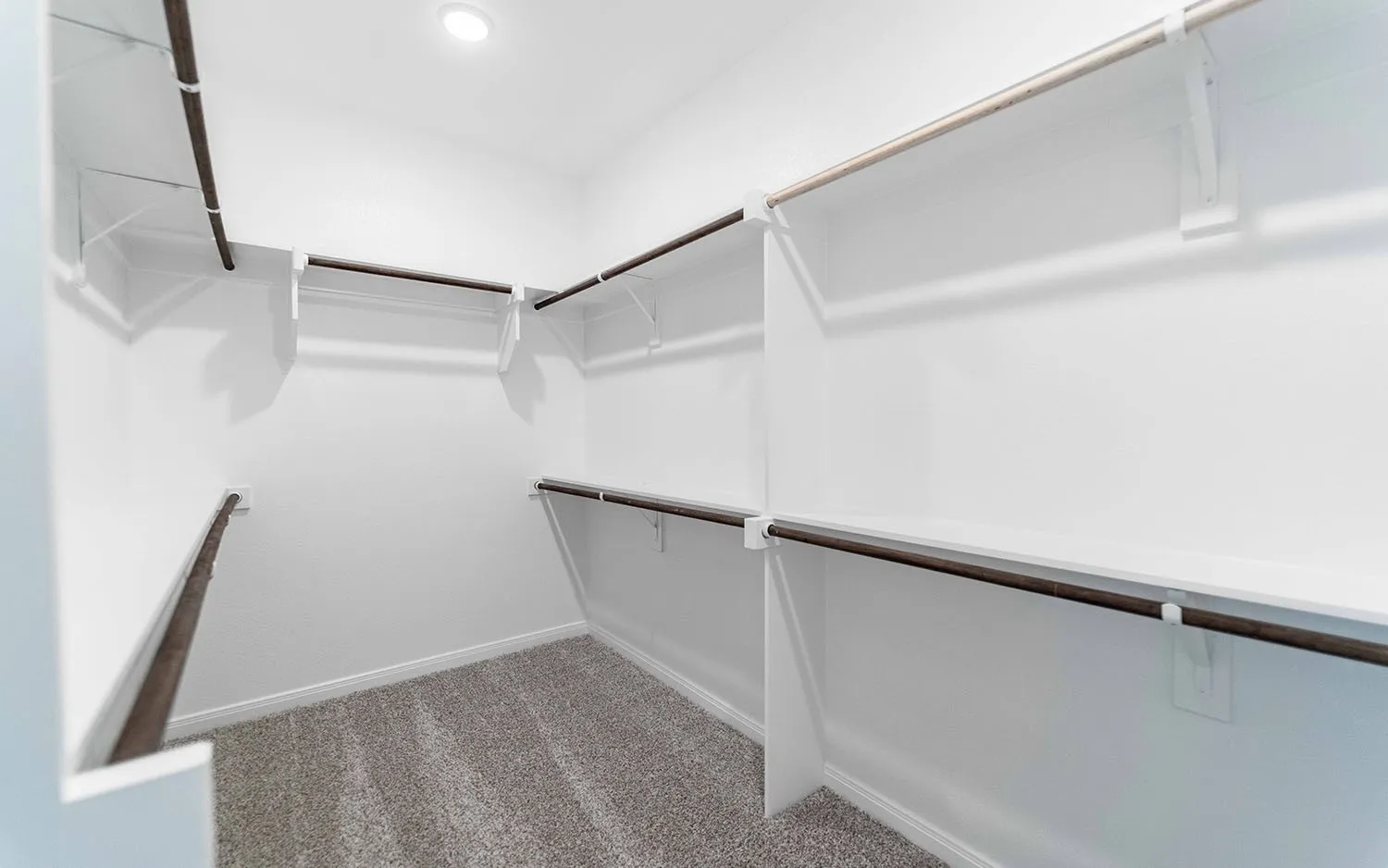 Walk-in closet with integrated shelving, multiple hanging rods, recessed ceiling lighting, and carpet flooring