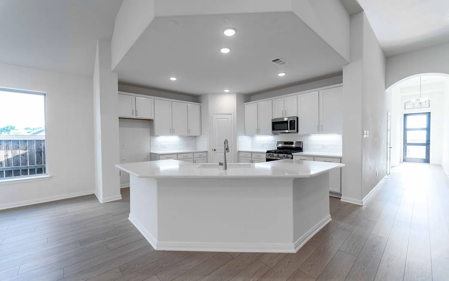 Kitchen featuring an island with white countertops, stainless steel appliances, recessed lighting, and wood-finish flooring