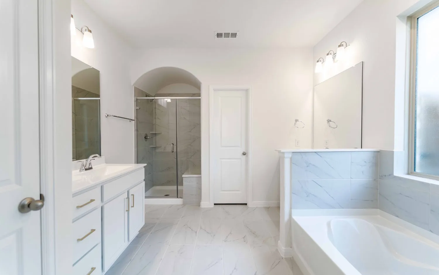 Spacious bathroom featuring a dual vanity, separate walk-in shower with glass enclosure, white soaking tub, and tile flooring