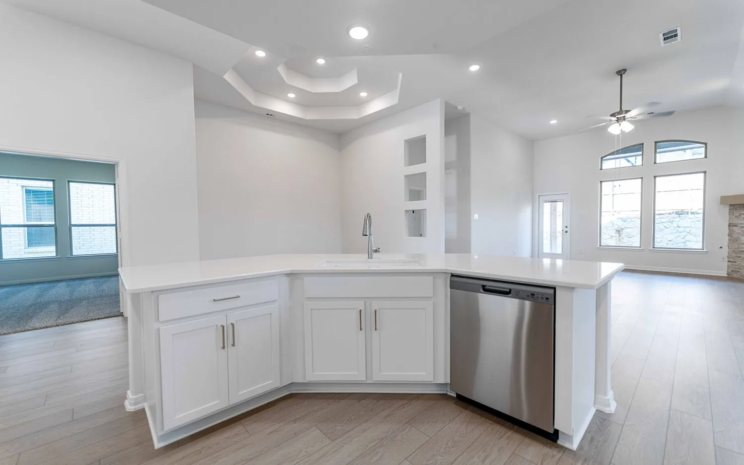 Kitchen island with white cabinetry, stainless steel dishwasher, and a single-basin sink