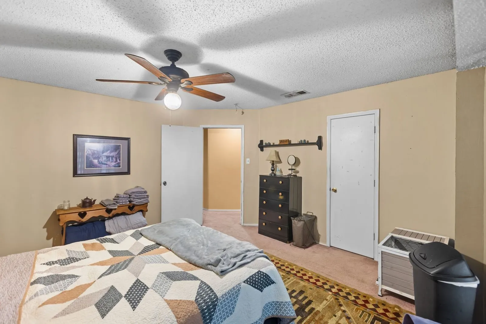 Ceiling fan with wood-finish blades, light beige wall paint, and white trim doors