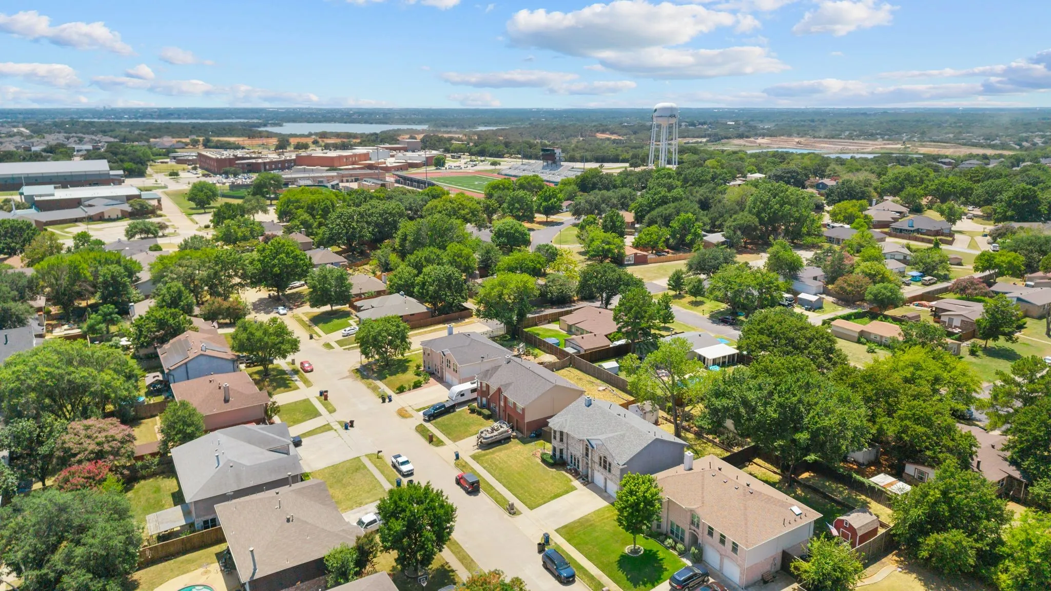 Established neighborhood with mature trees, residential streets, and a water tower in the distance