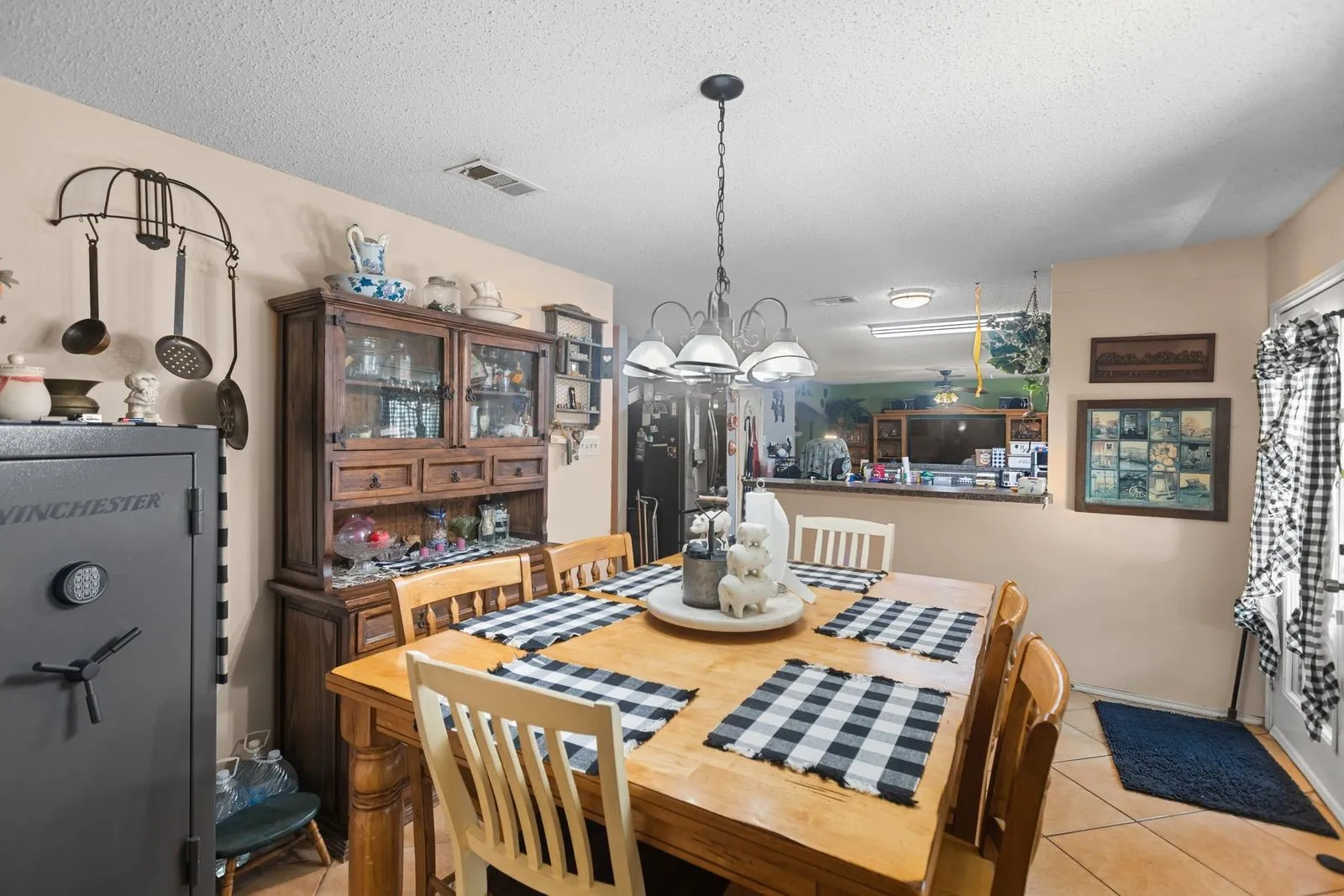 Recessed lighting and a decorative chandelier illuminate this space, featuring tile flooring and a built-in wooden display cabinet