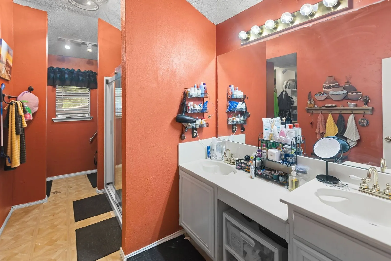 Double vanity with integrated sinks, expansive wall-mounted mirror, and overhead strip lighting