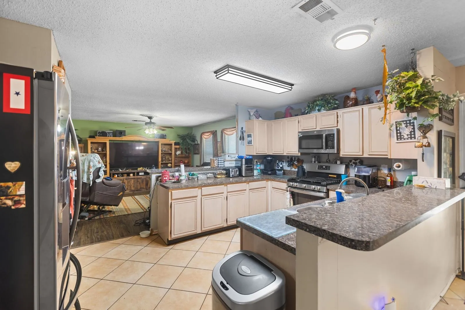 Kitchen featuring light-toned cabinetry, dark speckled countertops, stainless steel appliances, and tile flooring