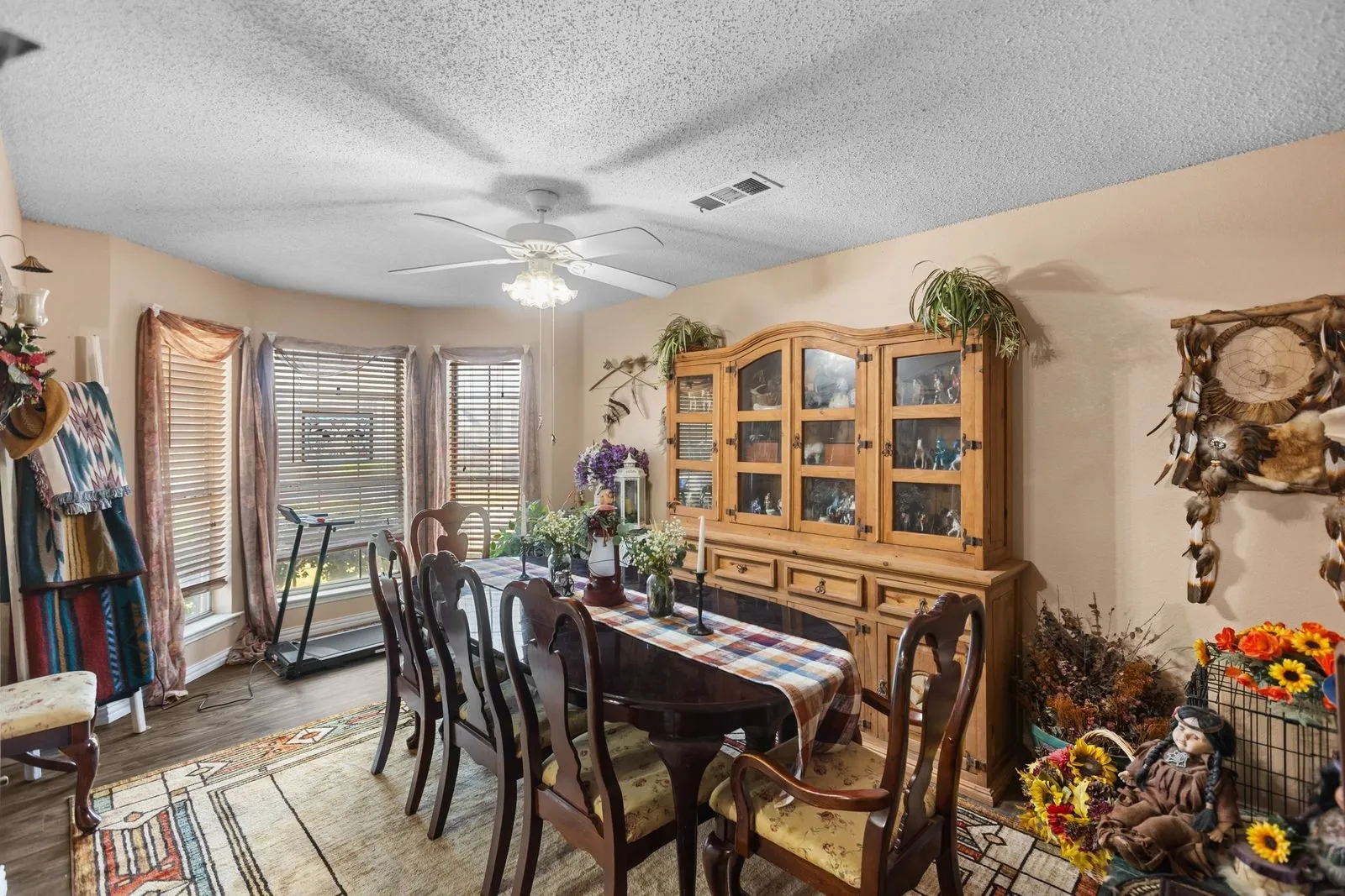 Bay window with multiple panes, wood-finish flooring, and a ceiling fan with light fixture