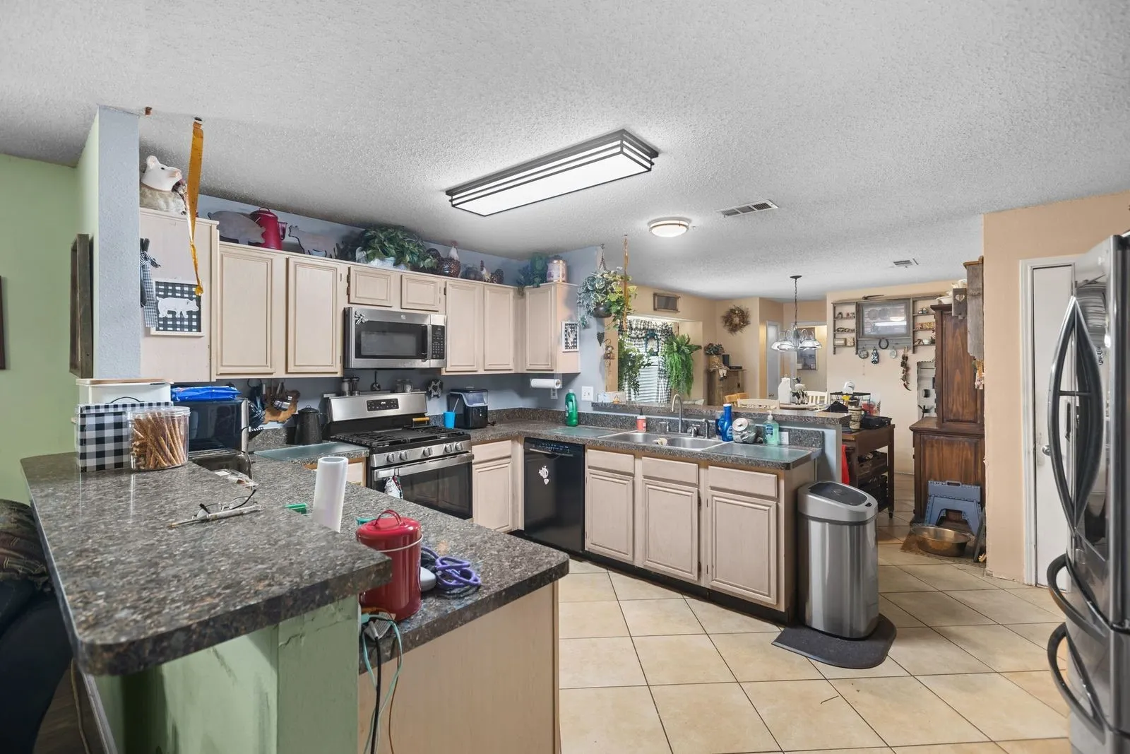 Kitchen featuring light-toned cabinetry, stainless steel appliances, a gas range, and a breakfast bar with an integrated sink