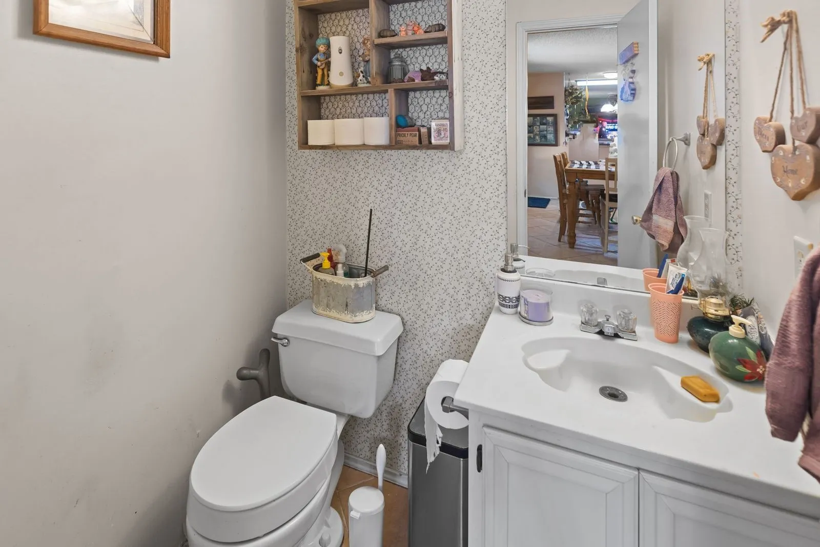 Vanity with integrated sink, white cabinetry, and wall-mounted mirror