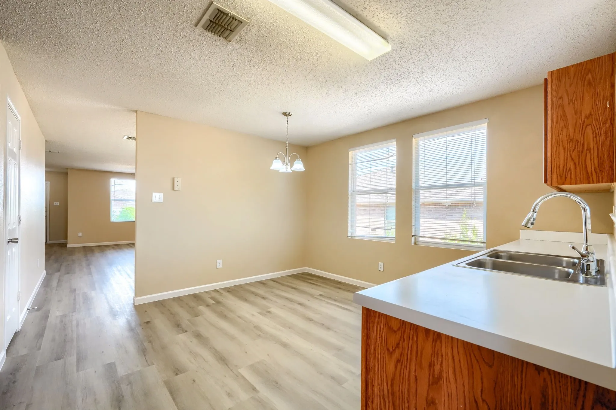 Spacious room with wood-finish flooring, neutral paint, and abundant natural light from multiple windows