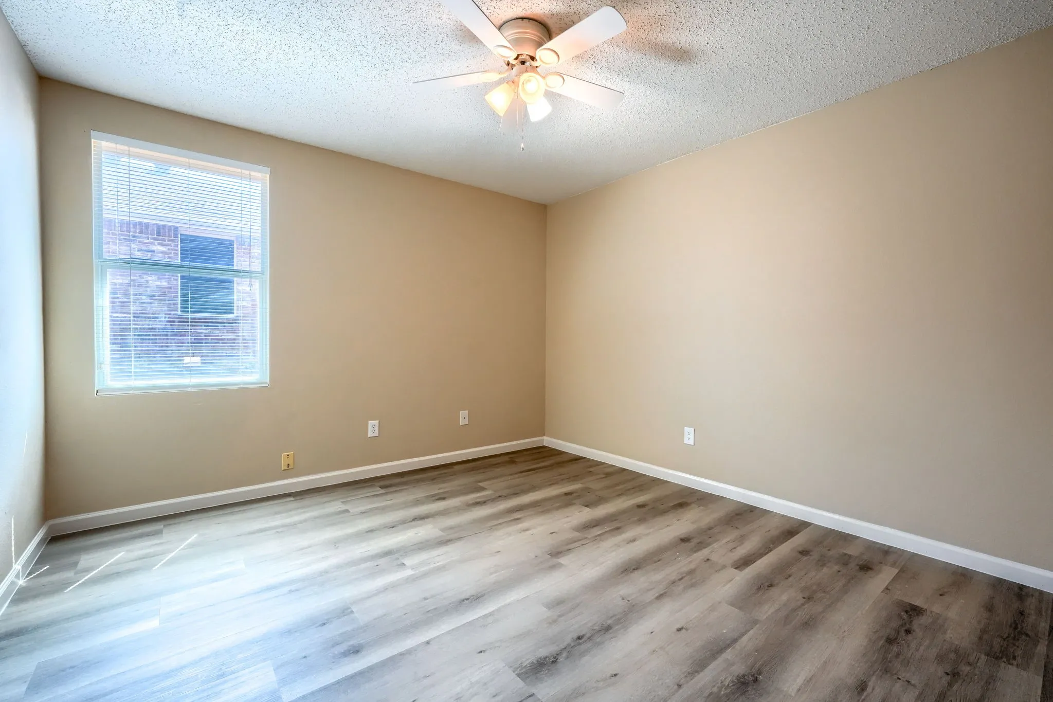 Wood-finish flooring, ceiling fan with integrated lighting, window with blinds, and neutral wall tones
