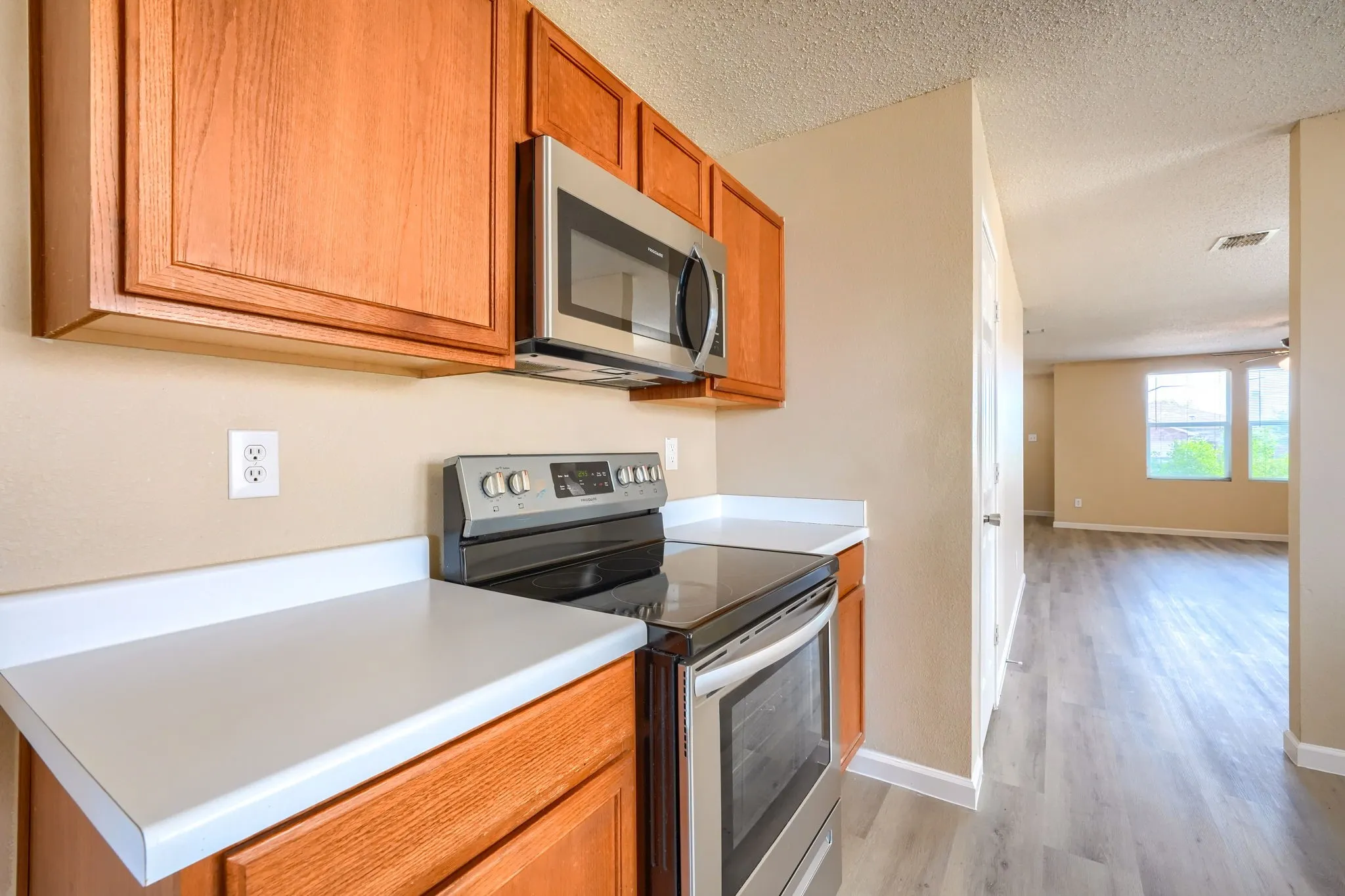 Kitchen featuring wood cabinetry, white countertops, stainless steel microwave, and stainless steel range