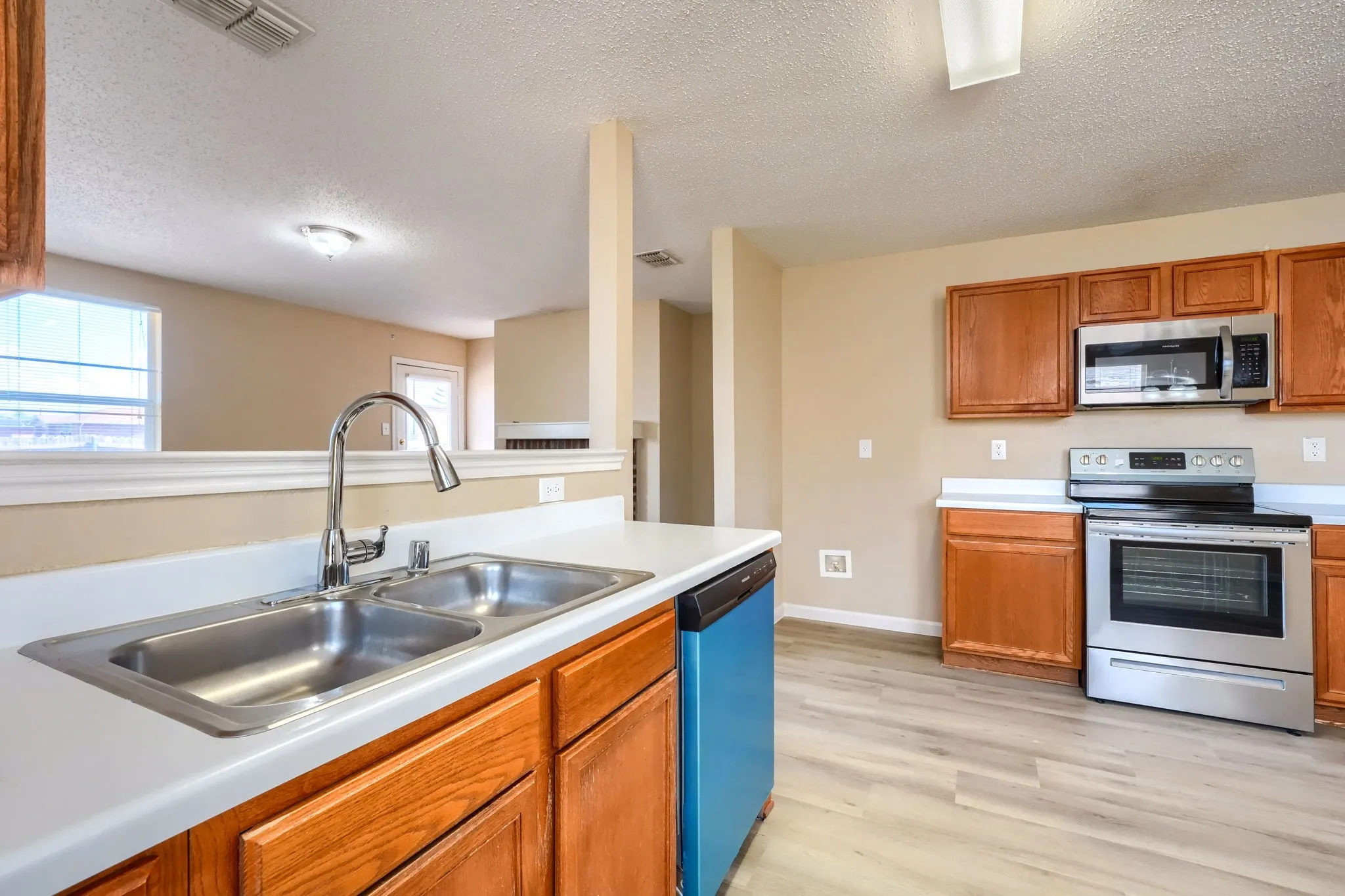 Kitchen featuring wood-finish cabinetry, stainless steel appliances, a double basin sink, and wood-finish flooring
