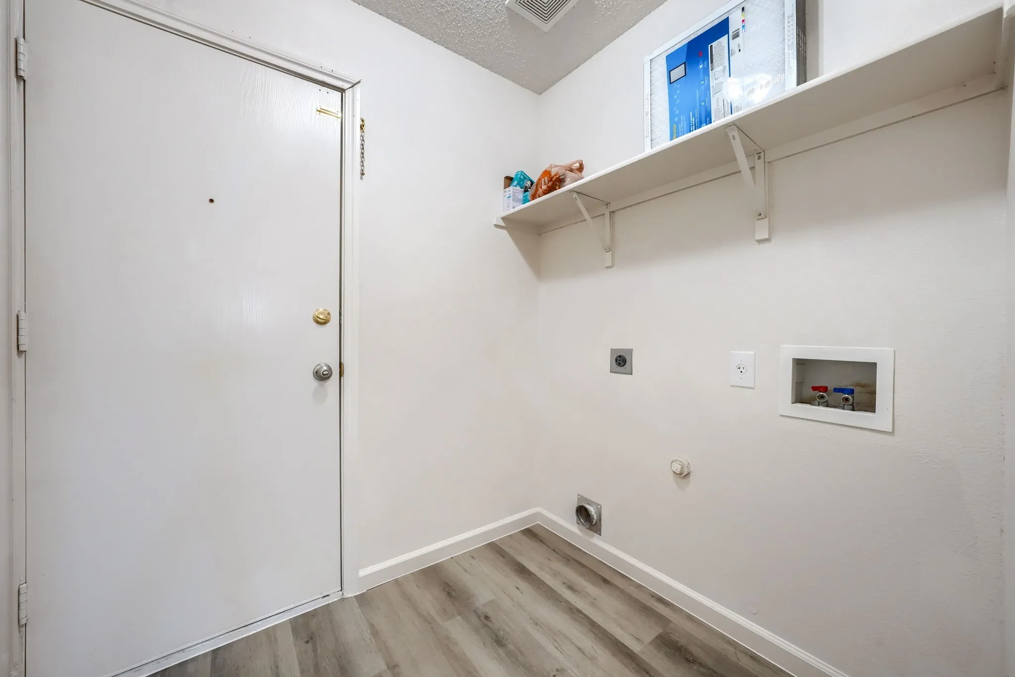 Utility room with wood-finish flooring, white walls, and built-in shelving