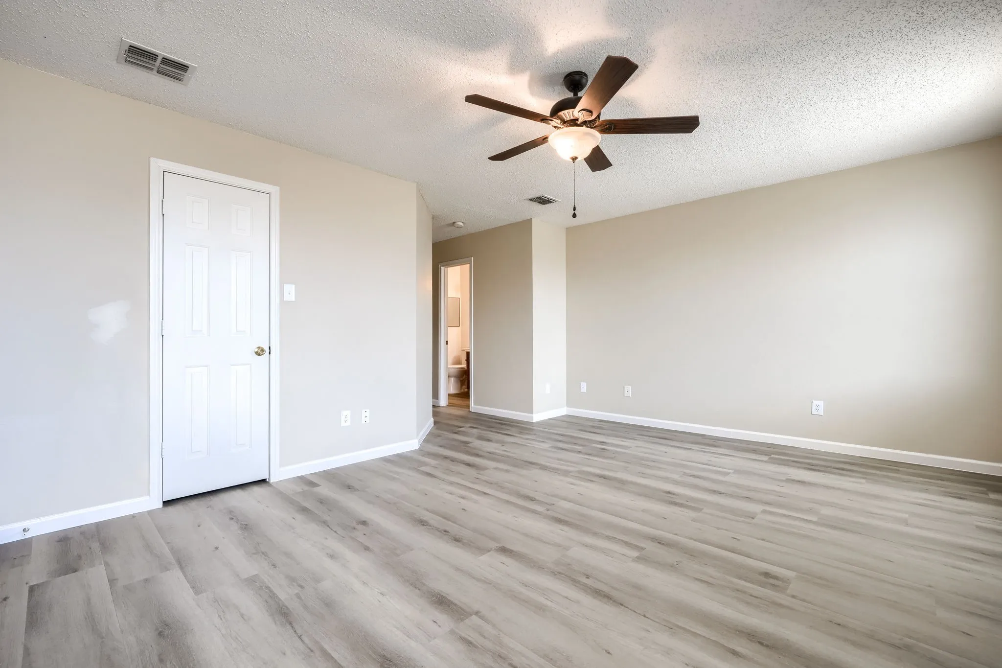 Wood-finish flooring, neutral wall tones, and an overhead ceiling fan with lighting