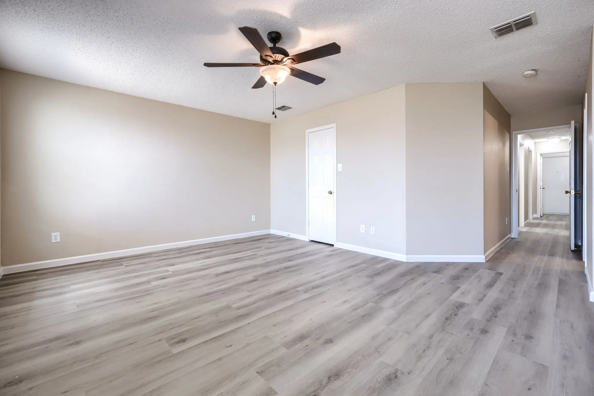 Spacious room featuring wood-finish flooring, a ceiling fan with integrated lighting, and neutral wall tones