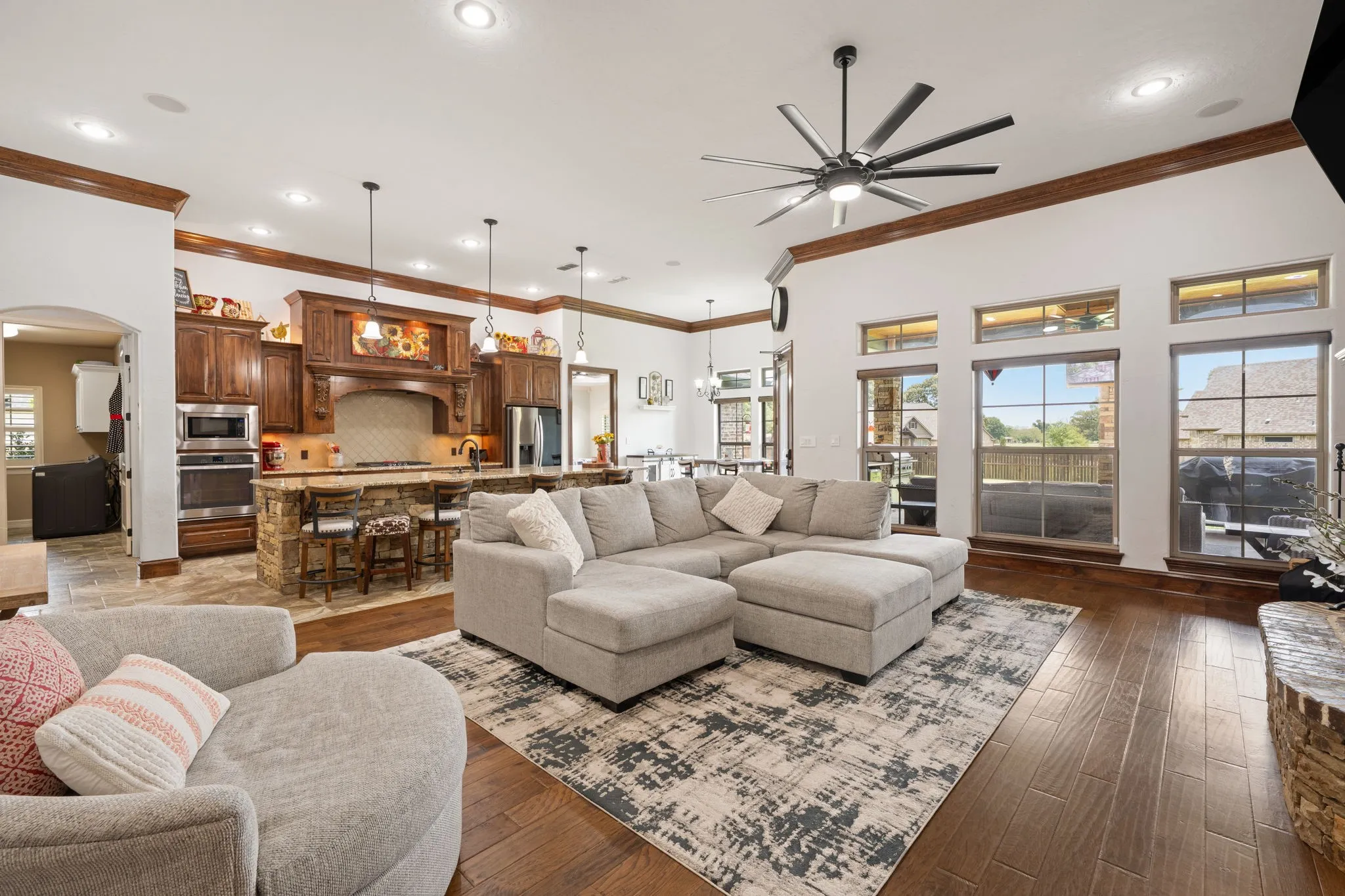 Open-concept living area with wood-finish flooring, a contemporary ceiling fan, and recessed lighting