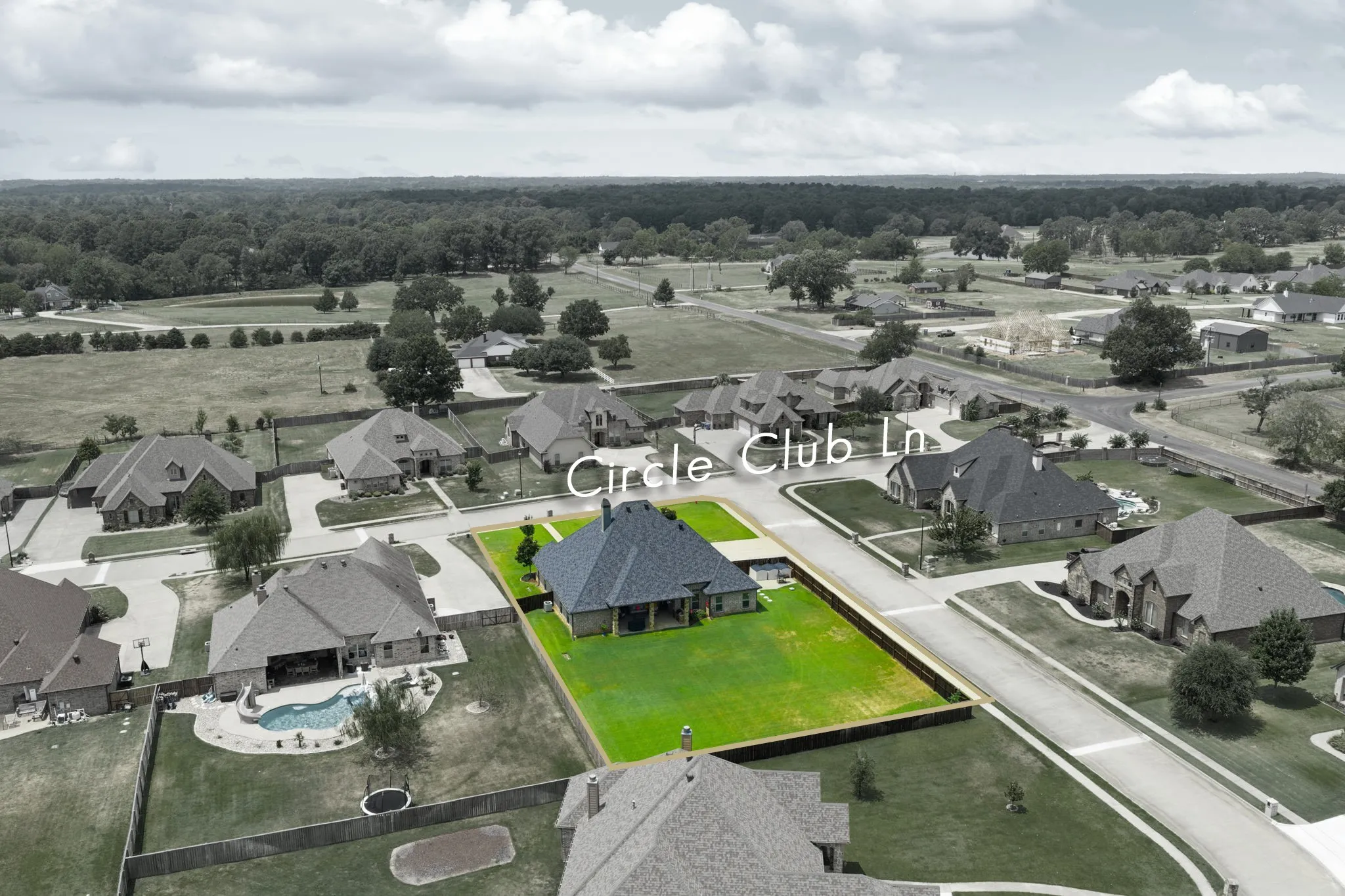 Aerial view showcasing this residential estate featuring a manicured lawn, dark-finished roof, and modern architectural design set on expansive grounds