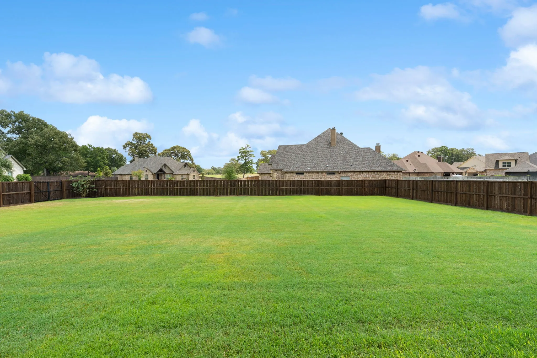 Expansive green lawn with a perimeter wood fence