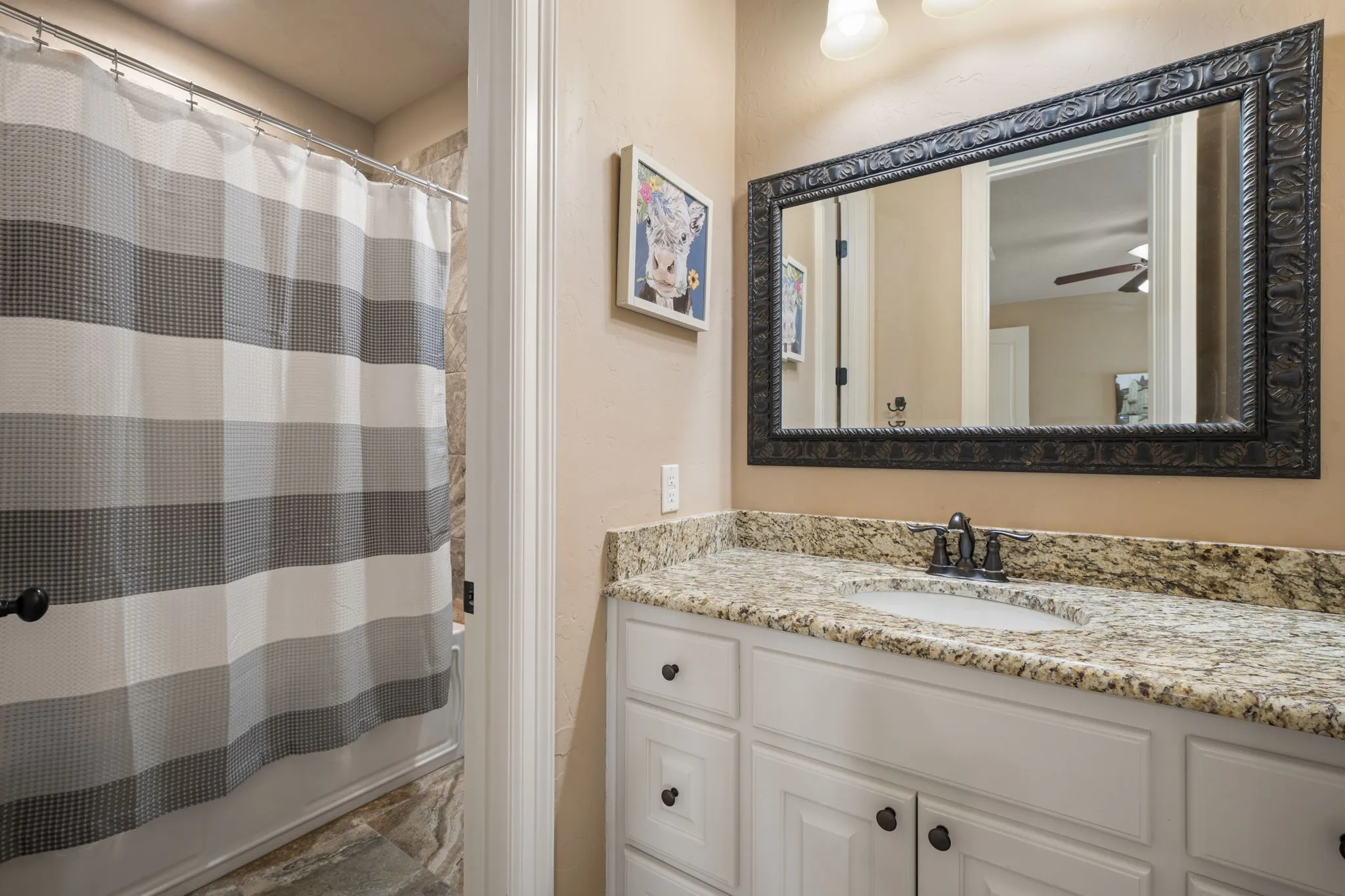 White vanity with panel-front cabinetry, granite countertop, undermount sink, and dark-finish faucet