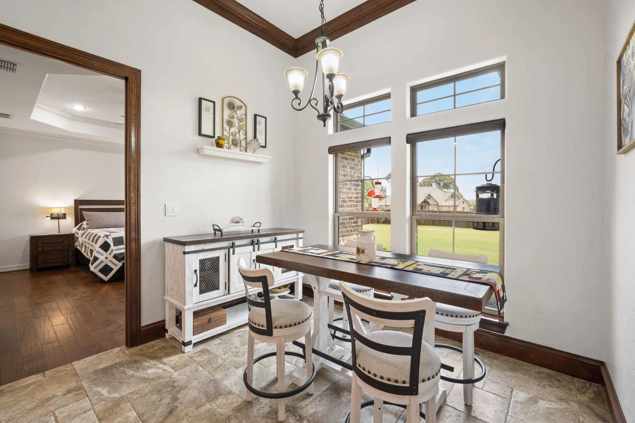 Bright home office featuring expansive windows with natural light, exposed wood-beam ceiling detail, and built-in cabinetry with integrated appliance