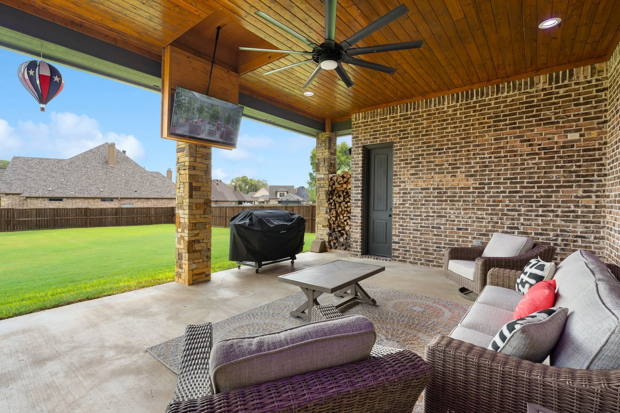 Covered patio with ceiling fan and recessed lighting, offering an expansive entertaining space overlooking a manicured lawn