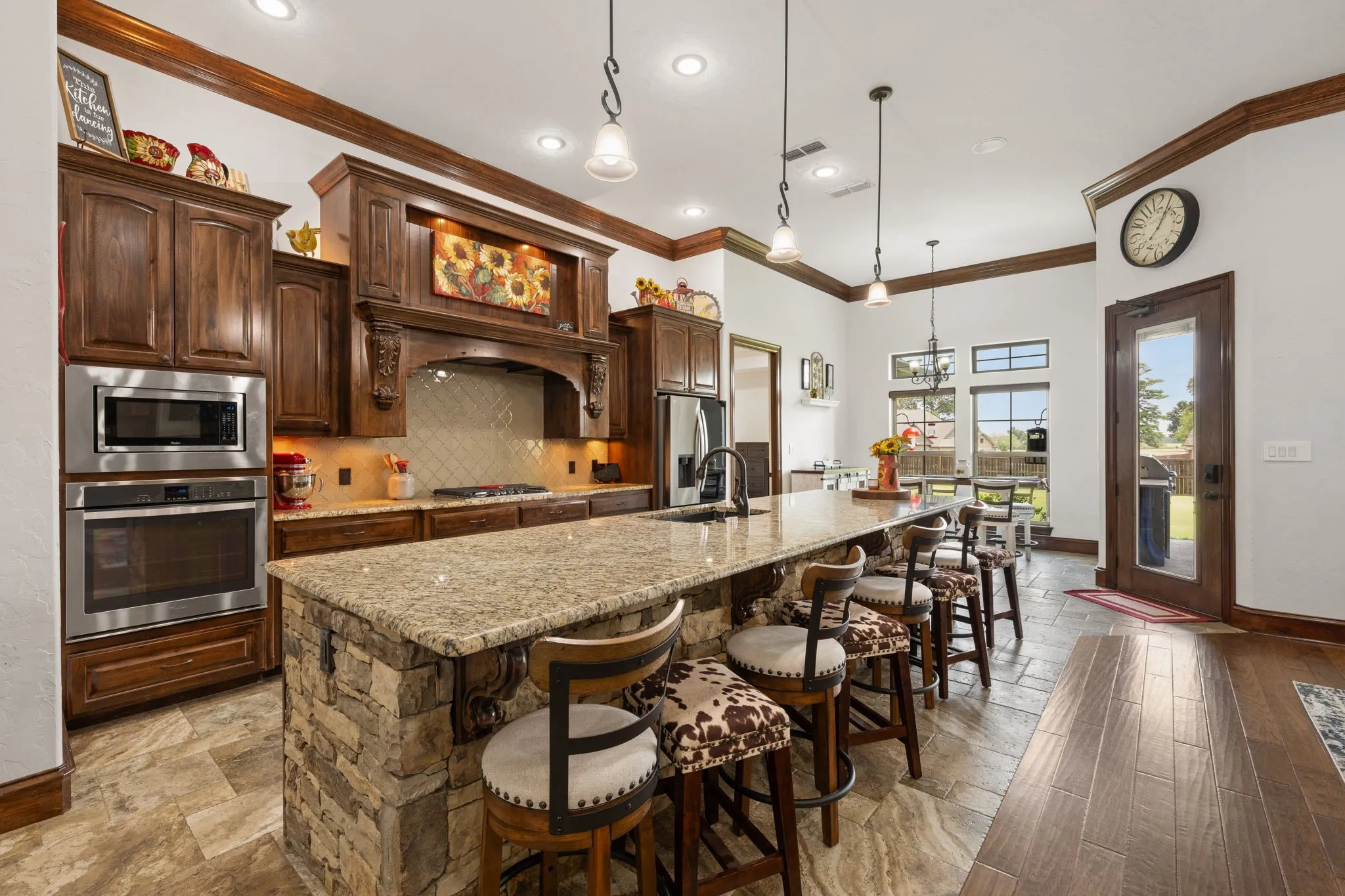 Gourmet kitchen featuring rich wood cabinetry, granite countertops, stainless steel appliances, and a substantial island with seating