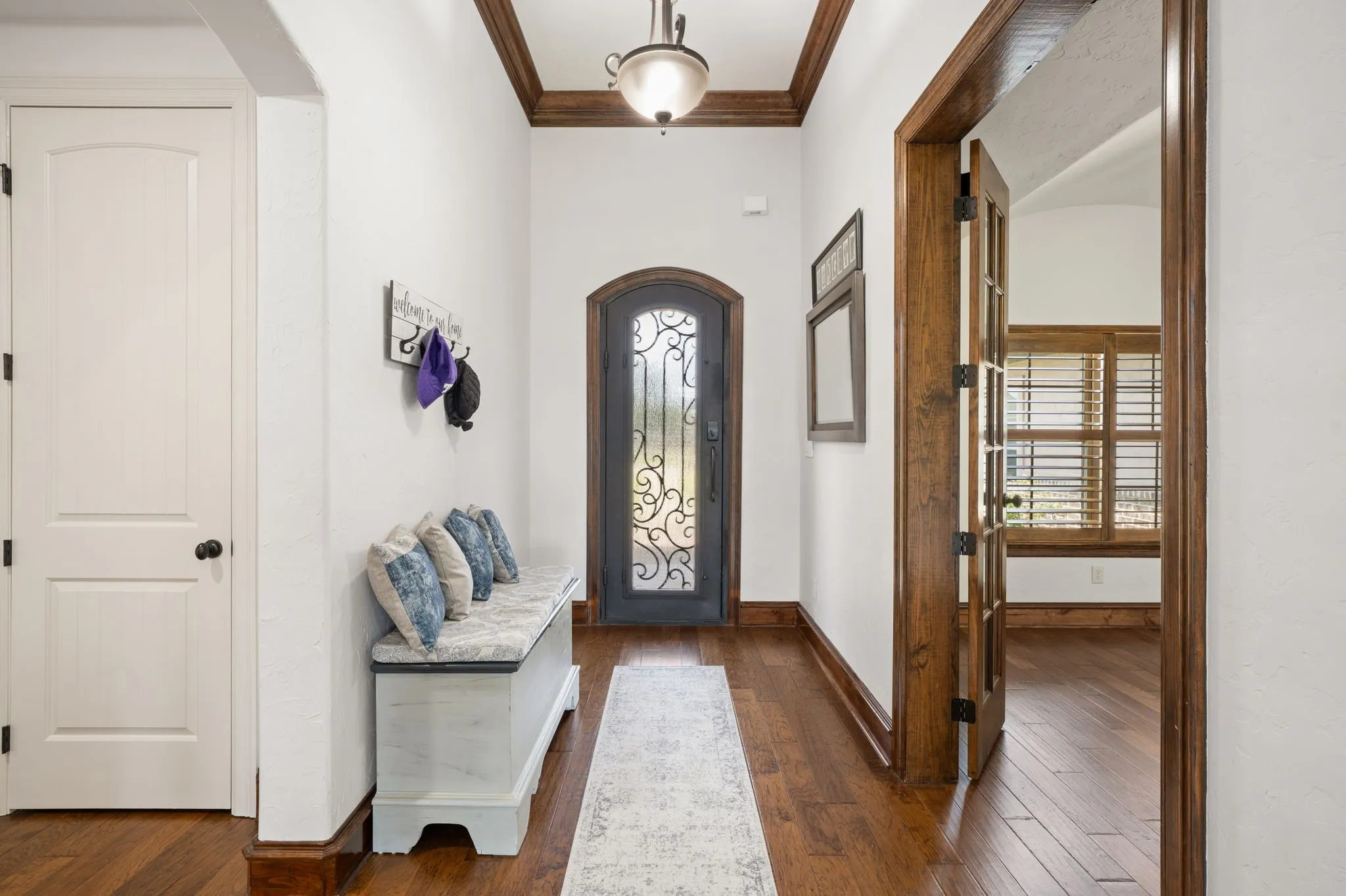 Elegant hallway showcasing rich wood-finish flooring, white walls, and coffered ceiling detail with integrated lighting