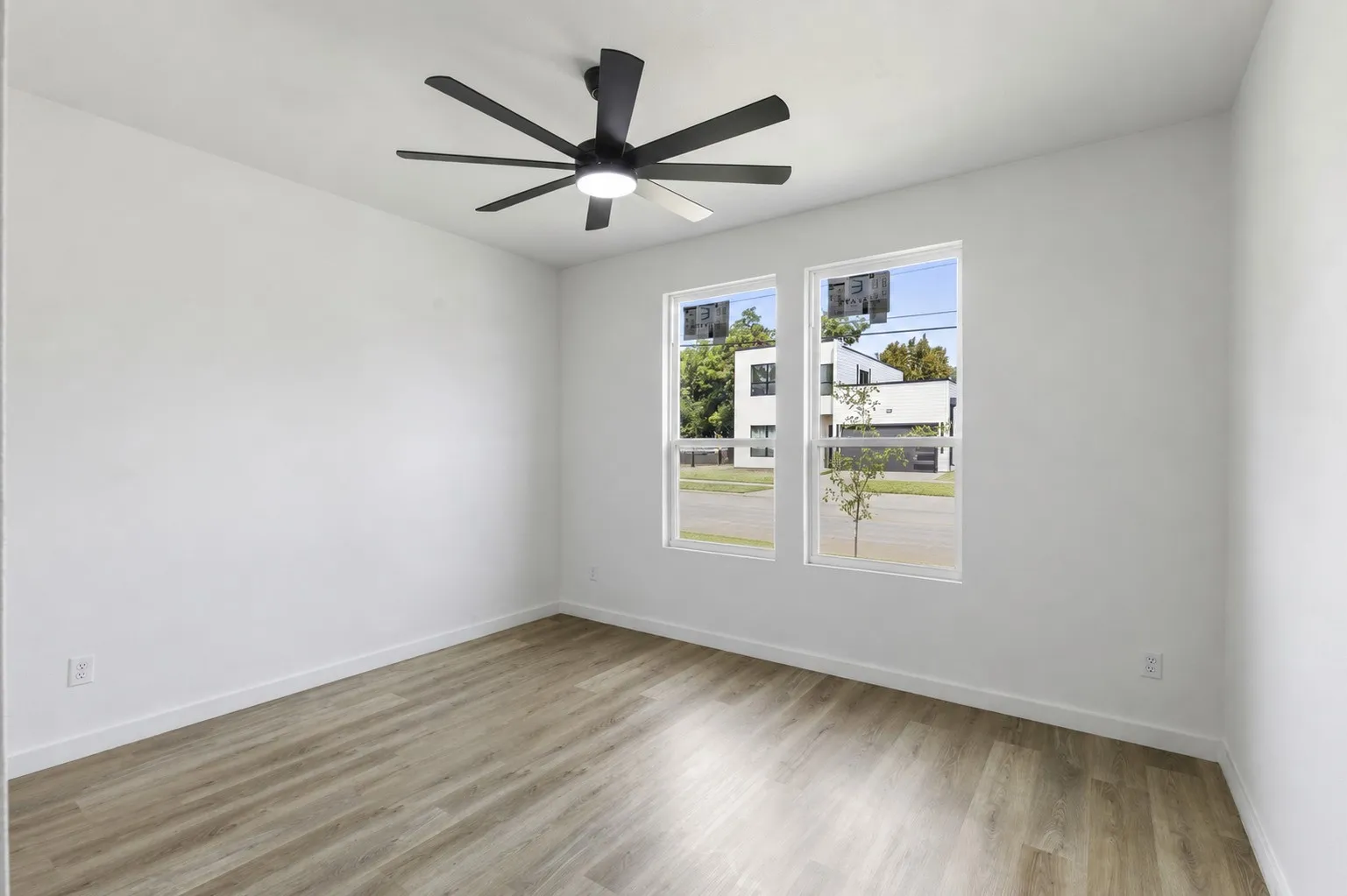 Wood-finish flooring, white walls, and a modern ceiling fan