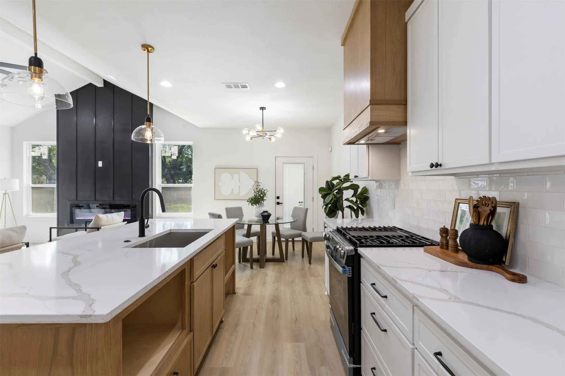 Kitchen with quartz countertops, wood-finish flooring, white cabinetry, and a built-in range