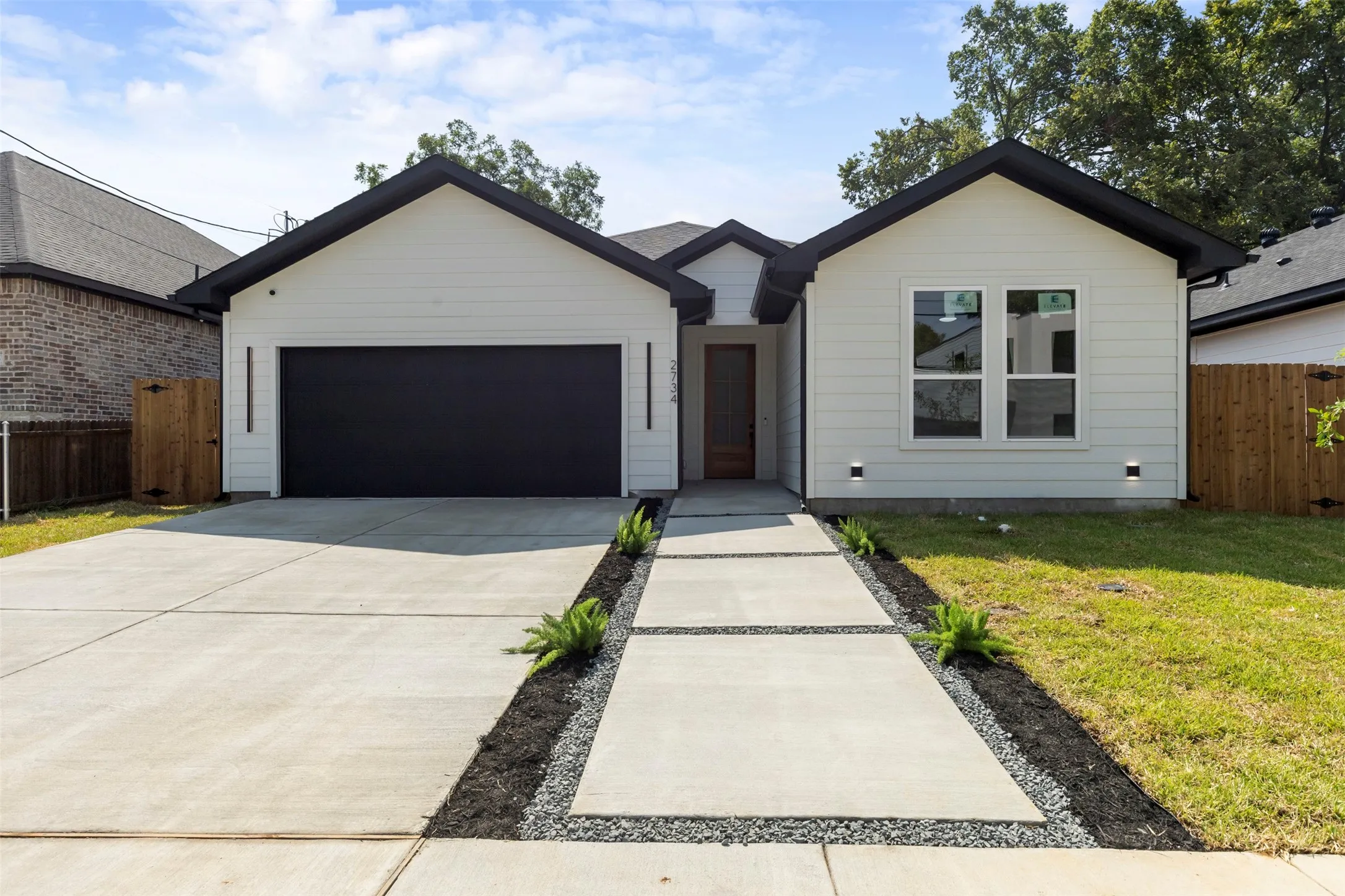 White horizontal siding exterior with a black roof and contrasting black garage door