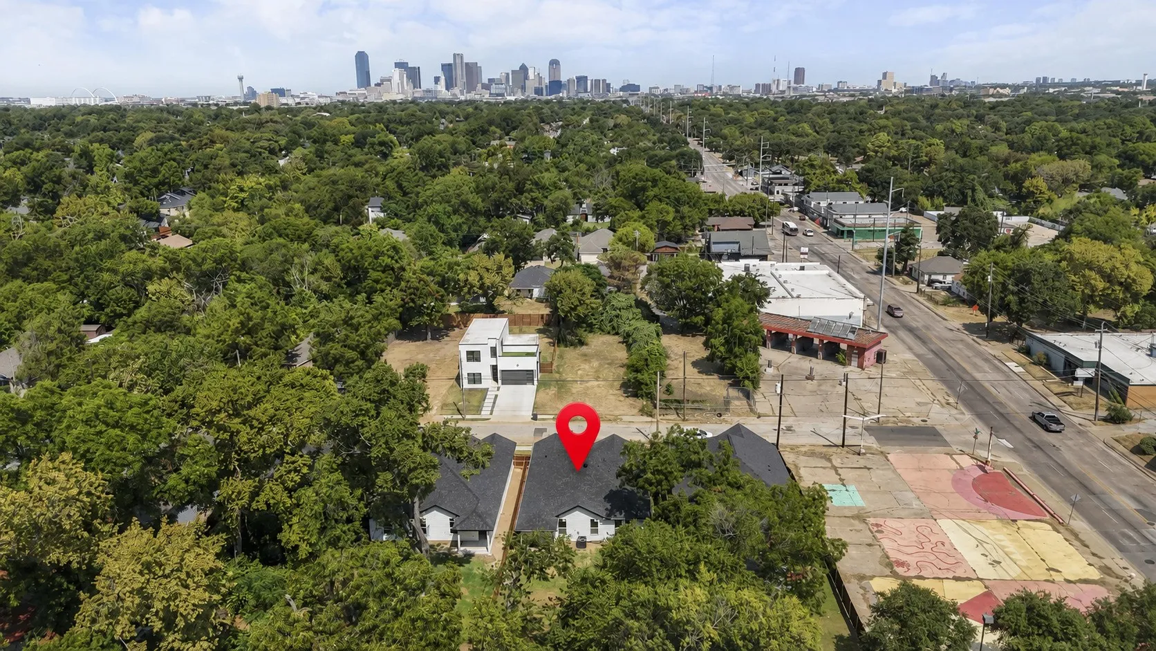 Contemporary residence with a dark-pitched roof, light-toned siding, and a prominent red location marker