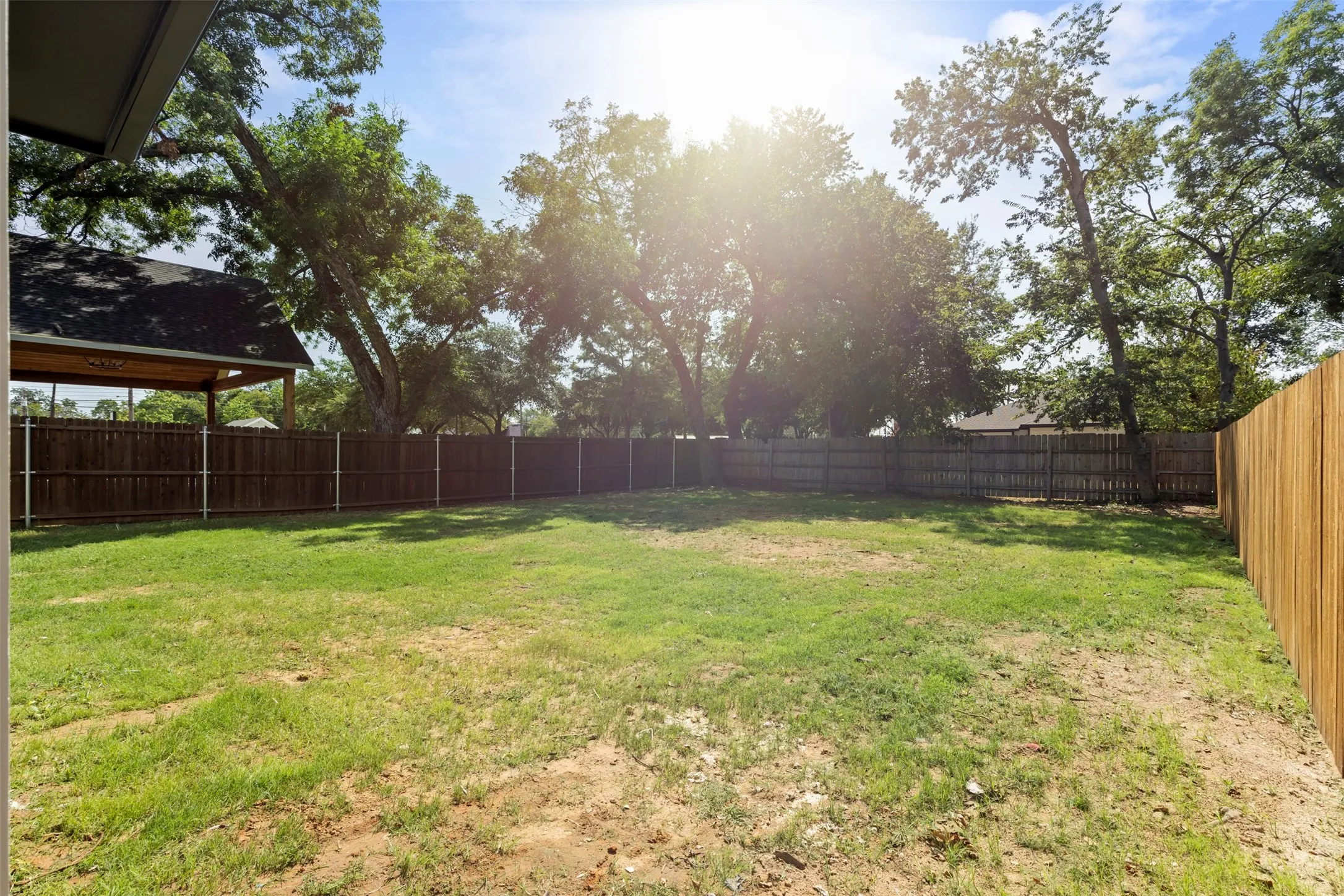 Expansive backyard featuring a manicured lawn, established perimeter fencing, and mature trees