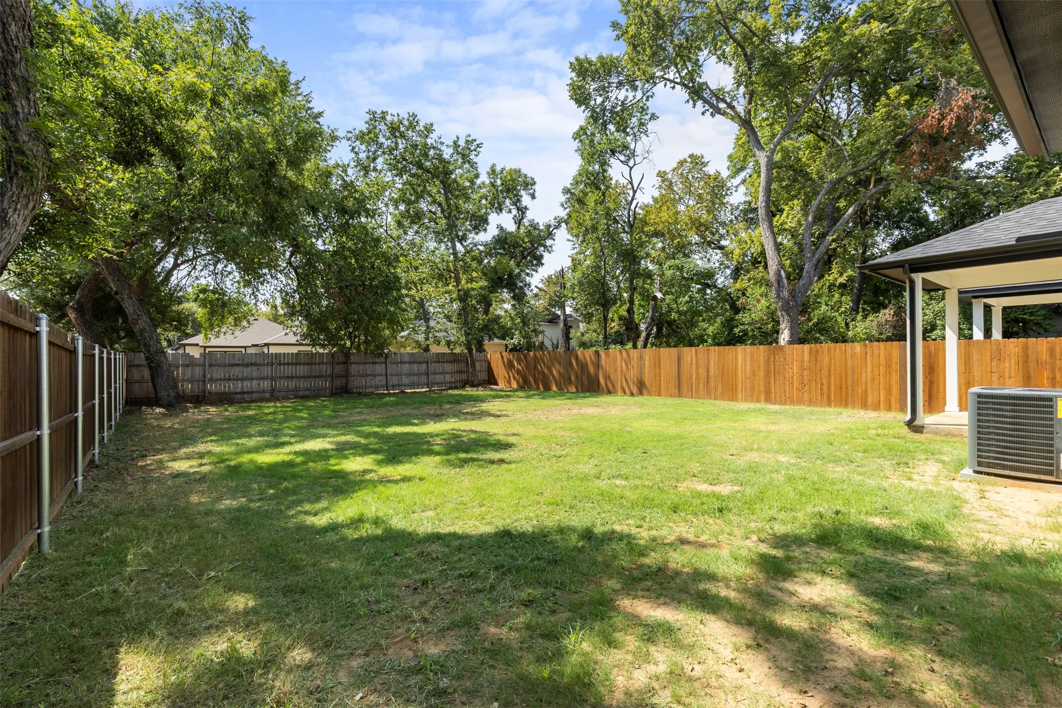 Expansive lawn area with a wood privacy fence and mature trees